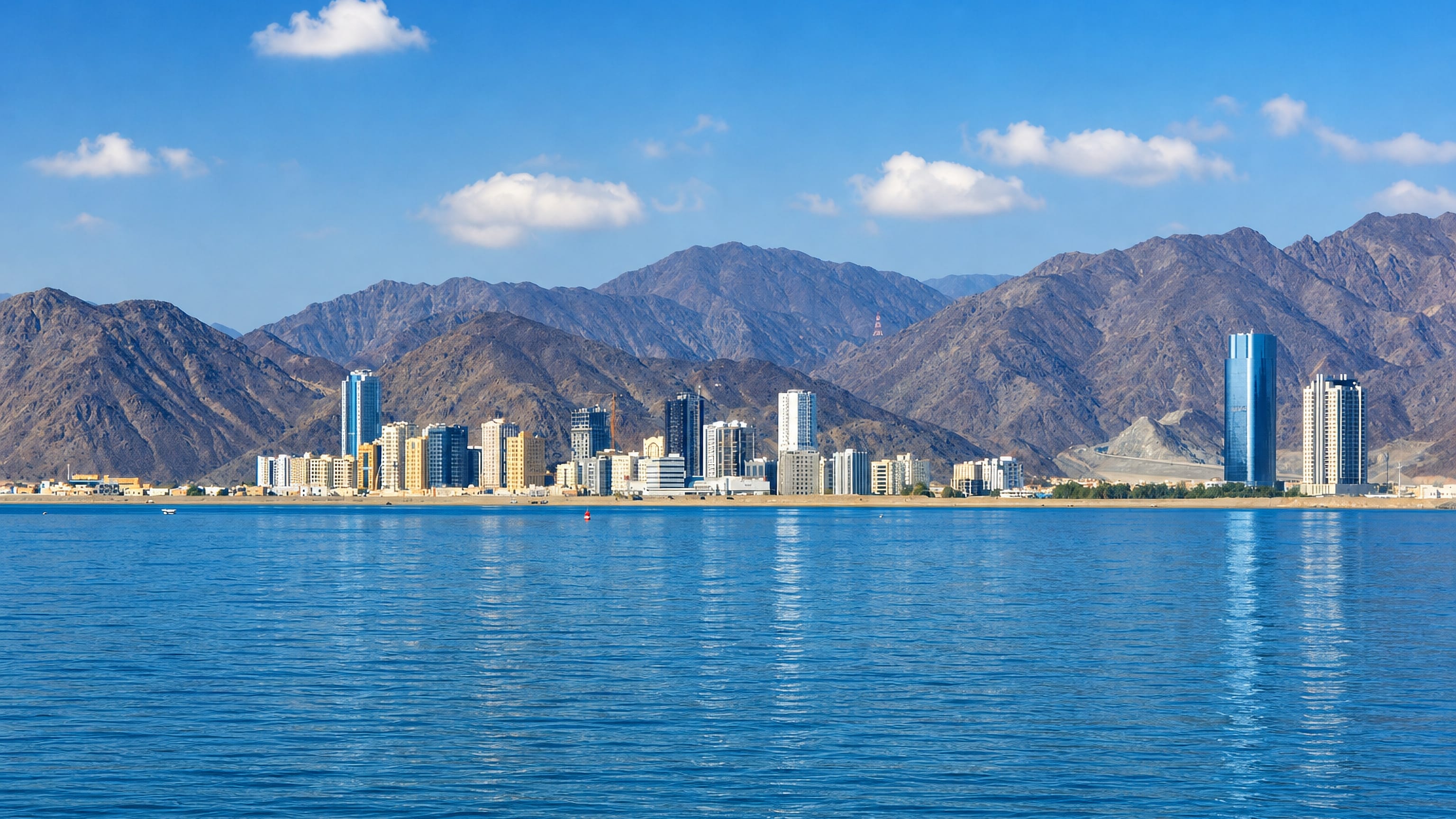 Fujairah's waterfront high-rises along the Gulf of Oman, backed by the rugged Hajar Mountains.