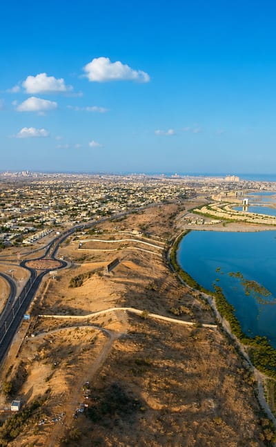 Aerial view of Ras Al Khaimah, a desert coastline with mangrove lagoons, a road interchange and a distant skyline.