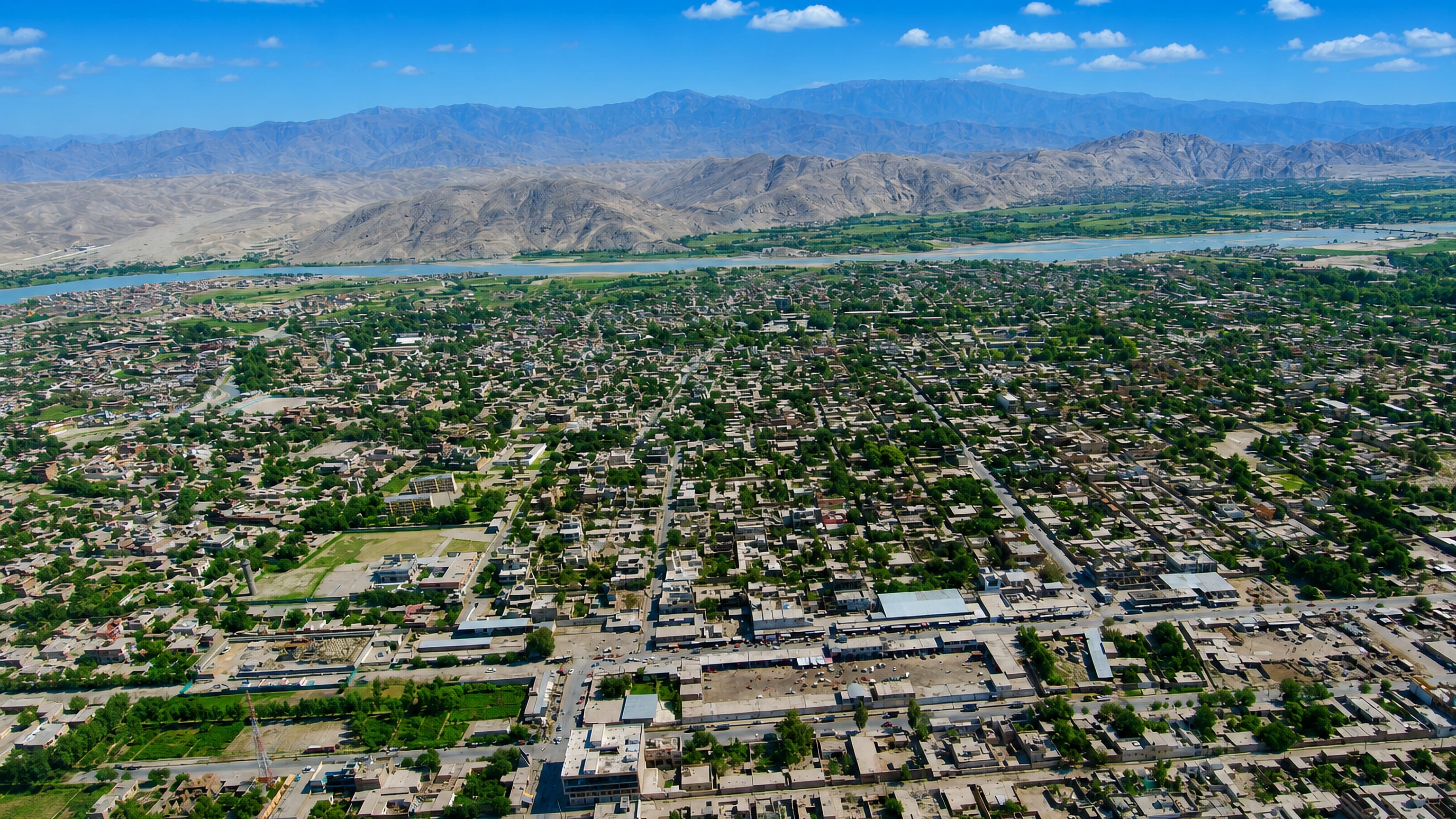Jalalabad's low-rise grid spreads across a green plain toward the Kabul River and bare Afghan ridges.