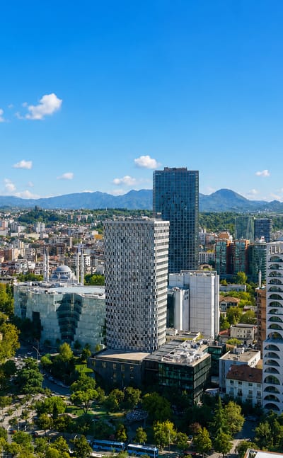 Tirana city center with modern towers, a mosque minaret and boulevards backed by mountains