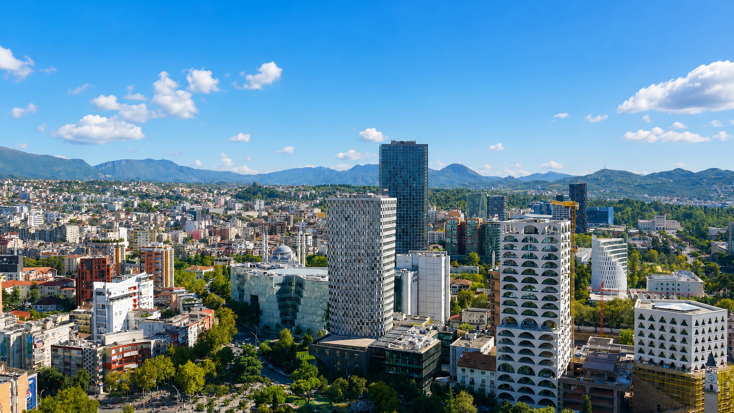 Tirana city center with modern towers, a mosque minaret and boulevards backed by mountains