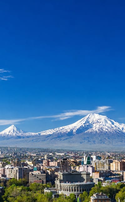 Yerevan cityscape below the snow-capped twin peaks of Mount Ararat under a clear blue sky