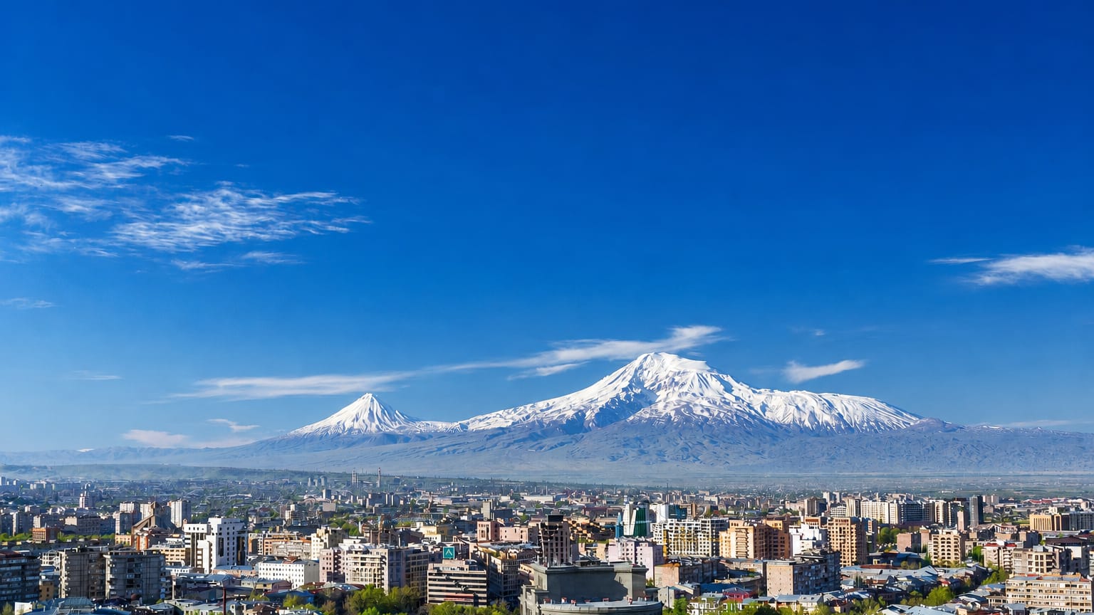Yerevan cityscape below the snow-capped twin peaks of Mount Ararat under a clear blue sky