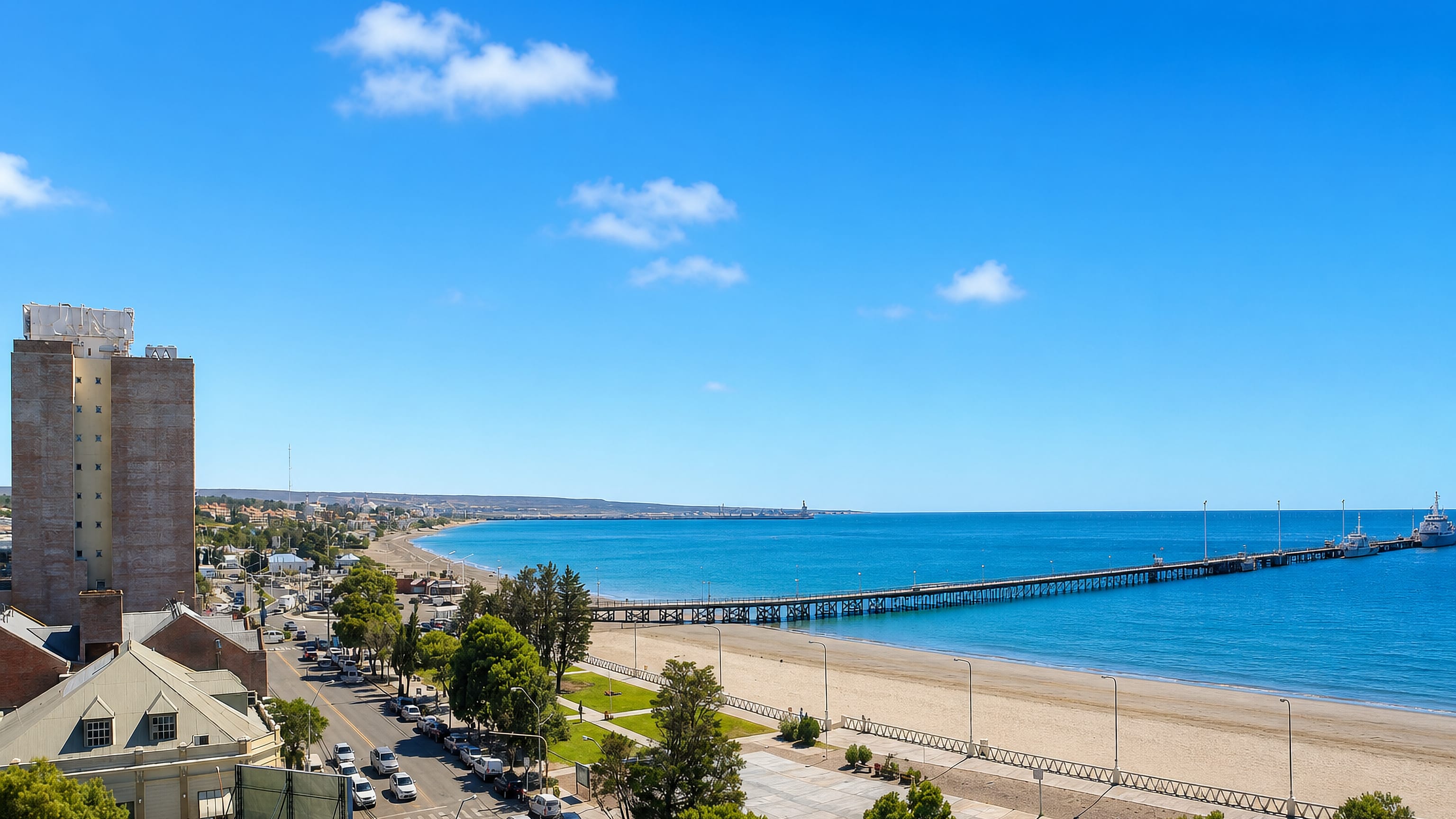 Puerto Madryn's long pier, sandy beach and coastal boulevard along the blue Golfo Nuevo, Patagonia, Argentina.