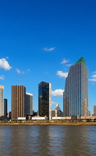 Buenos Aires waterfront skyline of modern glass towers, including a green-topped highrise, across the river.