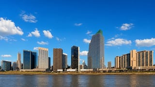 Buenos Aires waterfront skyline of modern glass towers, including a green-topped highrise, across the river.