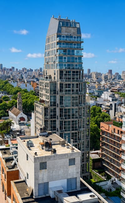Aerial of low-rise tree-lined streets and a slender modern tower in the Palermo Hollywood neighborhood of Buenos Aires