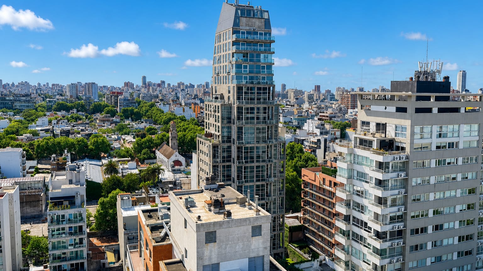 Aerial of low-rise tree-lined streets and a slender modern tower in the Palermo Hollywood neighborhood of Buenos Aires