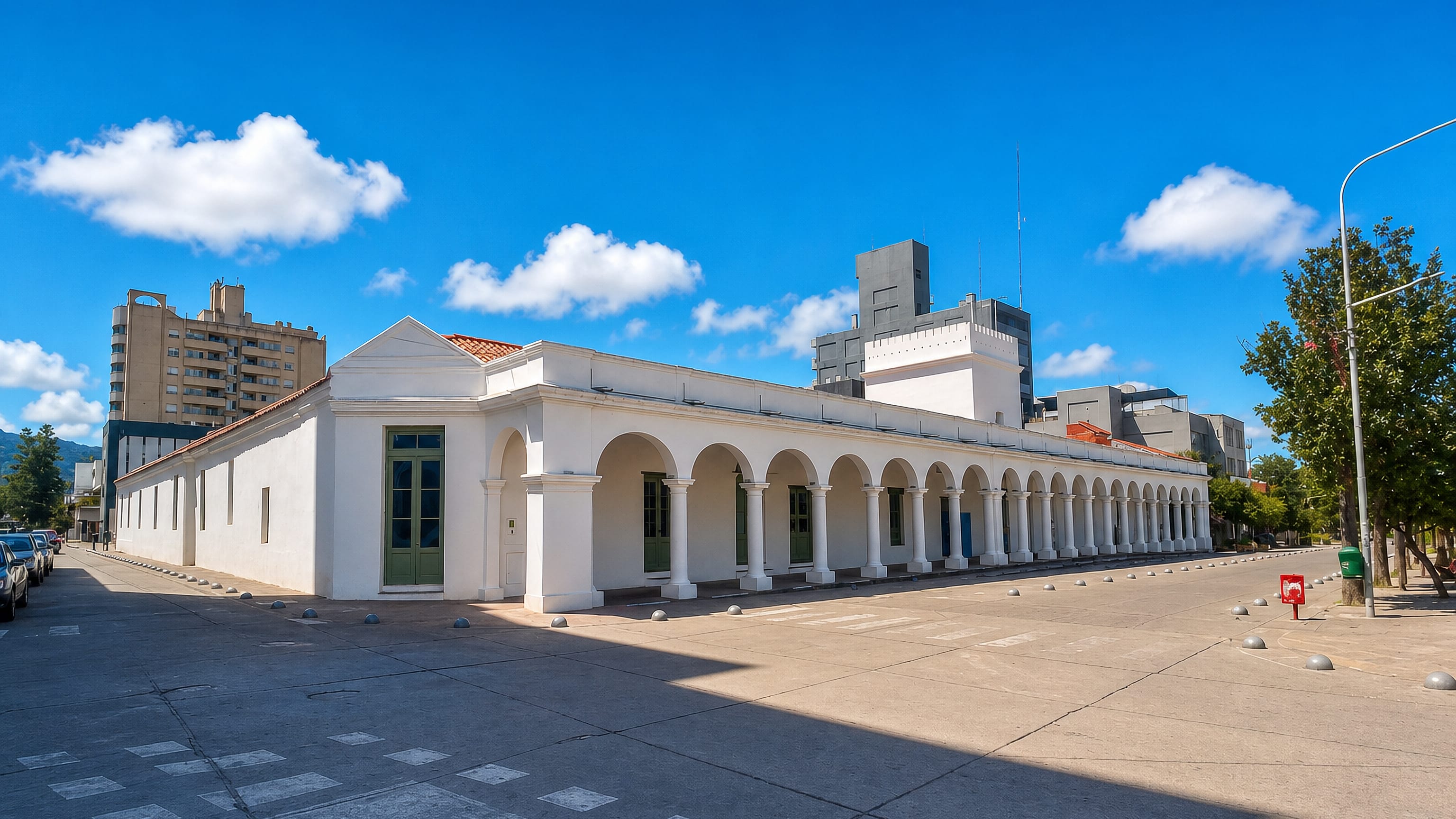 The long white arcade of the colonial Cabildo in San Salvador de Jujuy, with modern blocks and hills behind.
