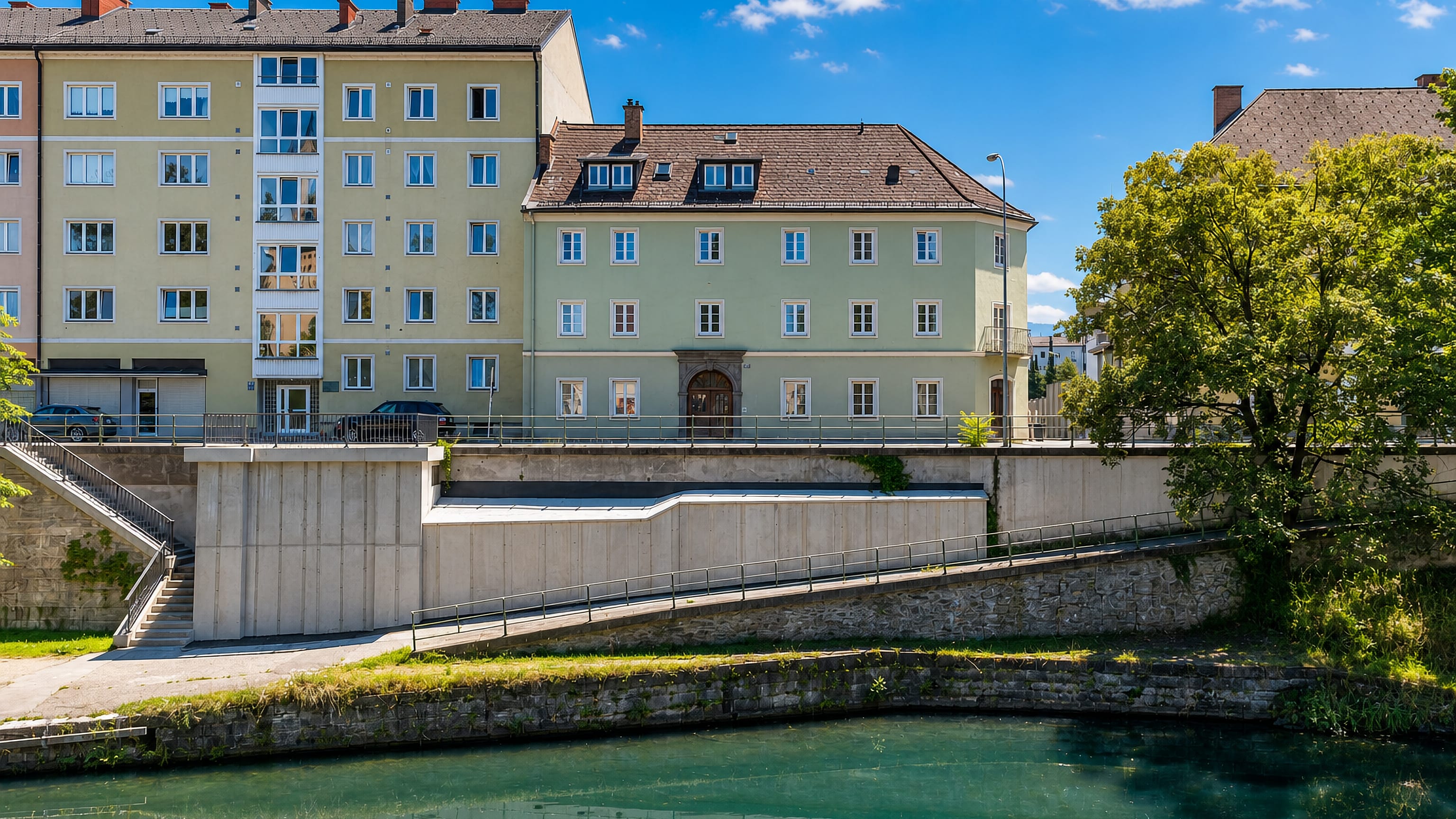 Pastel apartment houses above a turquoise canal embankment in Villacher Vorstadt, Klagenfurt.