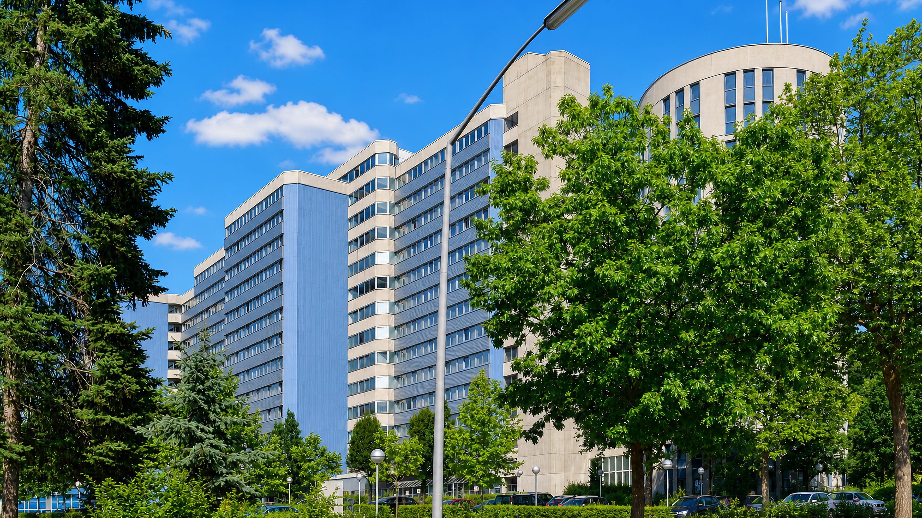 Modern concrete and glass campus buildings among trees in the Dornach-Auhof district of Linz.