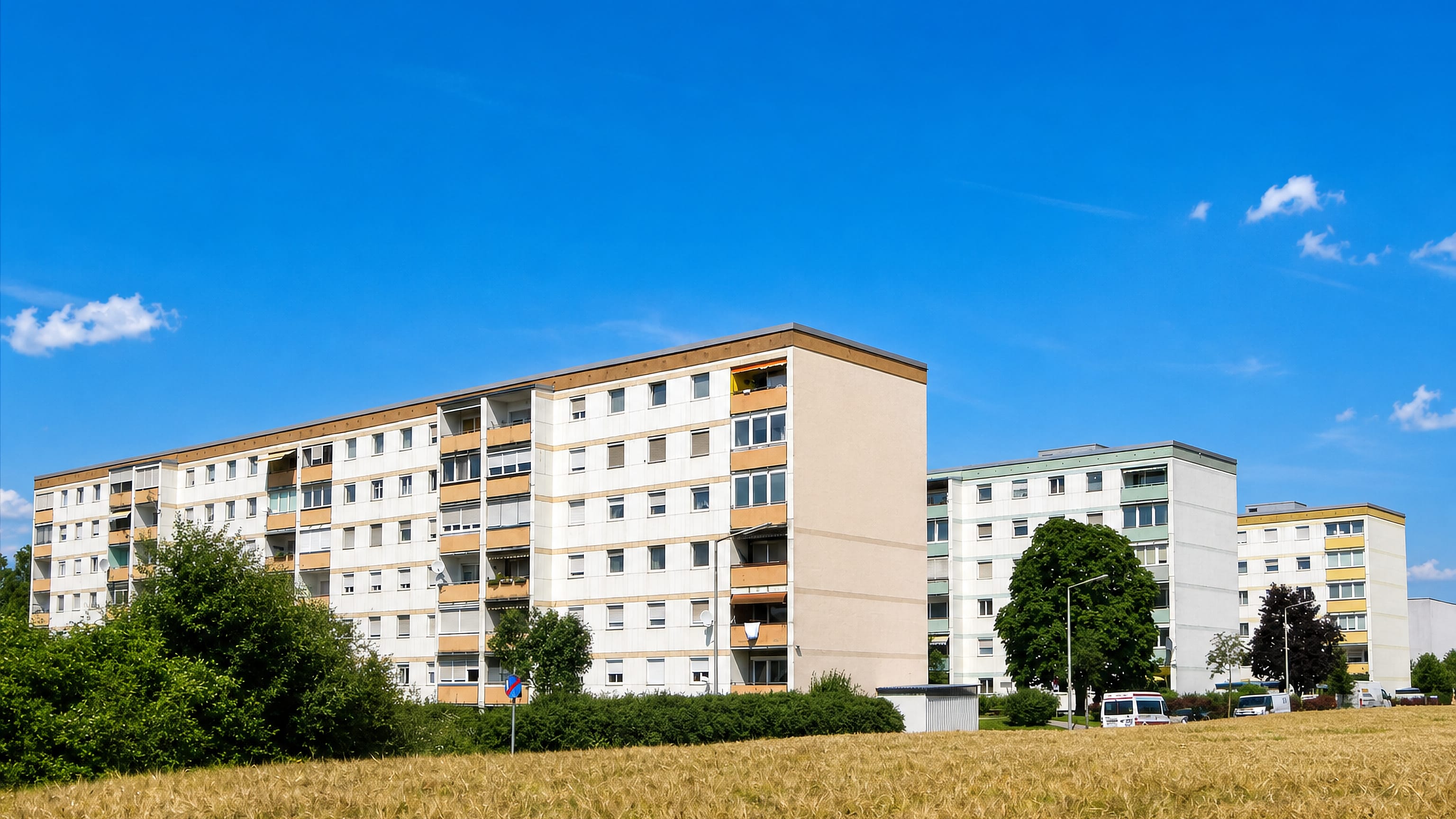 Post-war apartment slabs rising above an open field in Neue Heimat, a housing district of Linz.