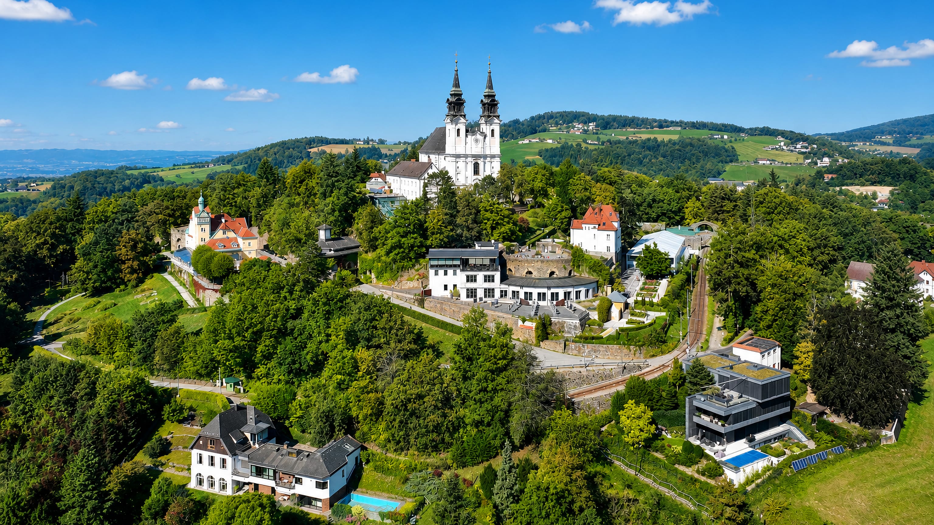 Twin-towered pilgrimage basilica on Postlingberg above Linz, mountain railway climbing the wooded hill.