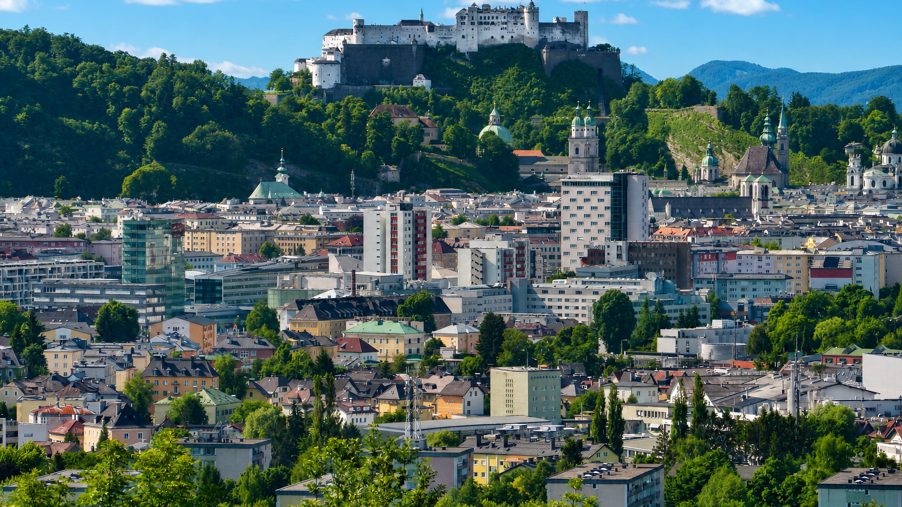 Hohensalzburg fortress and Salzburg's old-town towers seen across rooftops from Itzling to the north.