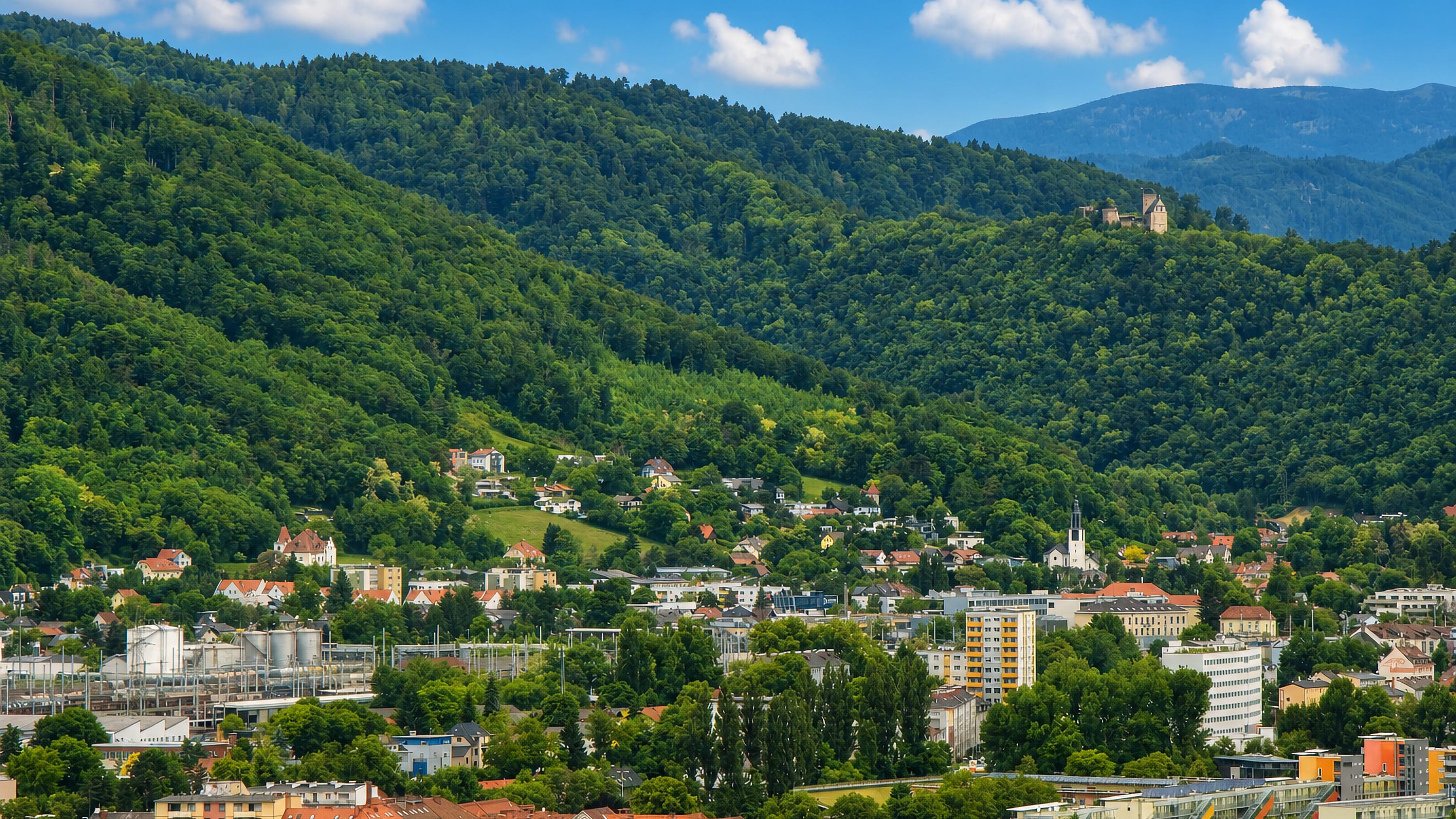 Wooded hills above Gösting in Graz, the castle ruin on the ridge and a church spire in the valley below