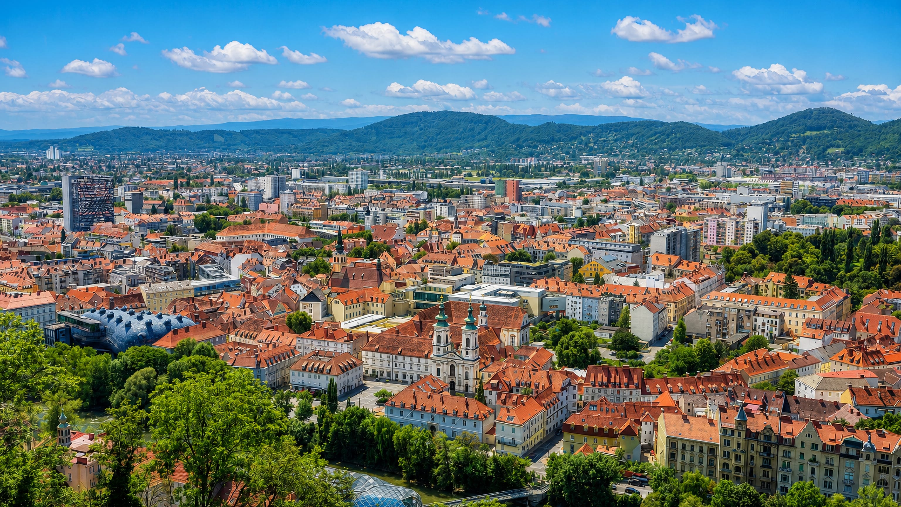 Graz old town from the Schlossberg, red-tiled roofs, the Kunsthaus and the Mur river below Styrian hills