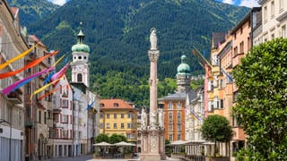 The Annasaeule column on Maria-Theresien-Strasse in Innsbruck, framed by pastel townhouses and Alpine slopes.