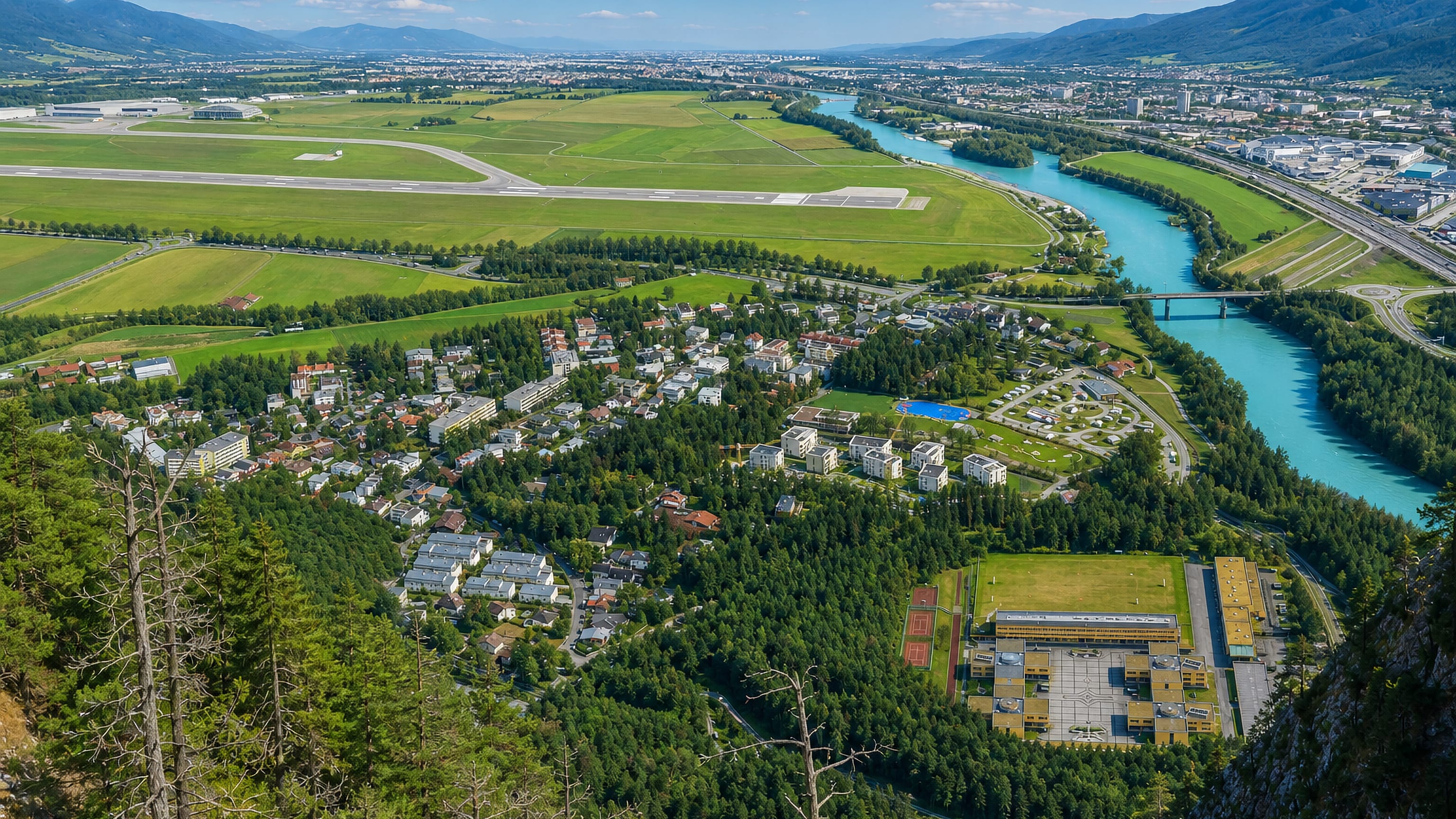 Aerial view of Kranebitten beside Innsbruck Airport, the turquoise Inn river and Tyrolean peaks.