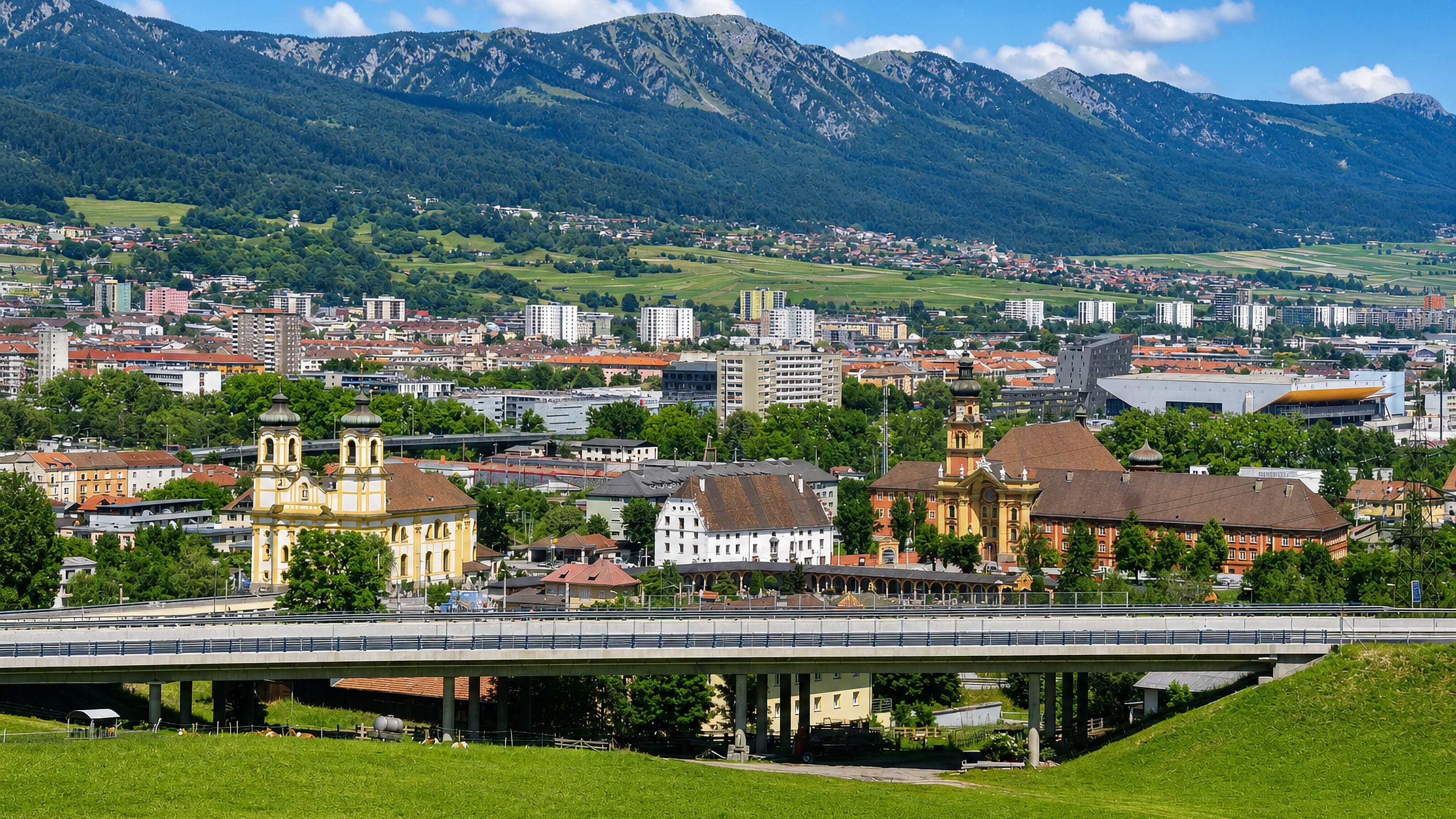 Wilten in Innsbruck with its yellow basilica towers and abbey church below the Alps and a motorway viaduct.