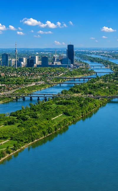Aerial of the Danube through Vienna near Döbling with bridges, green islands and the Donau City skyline beyond