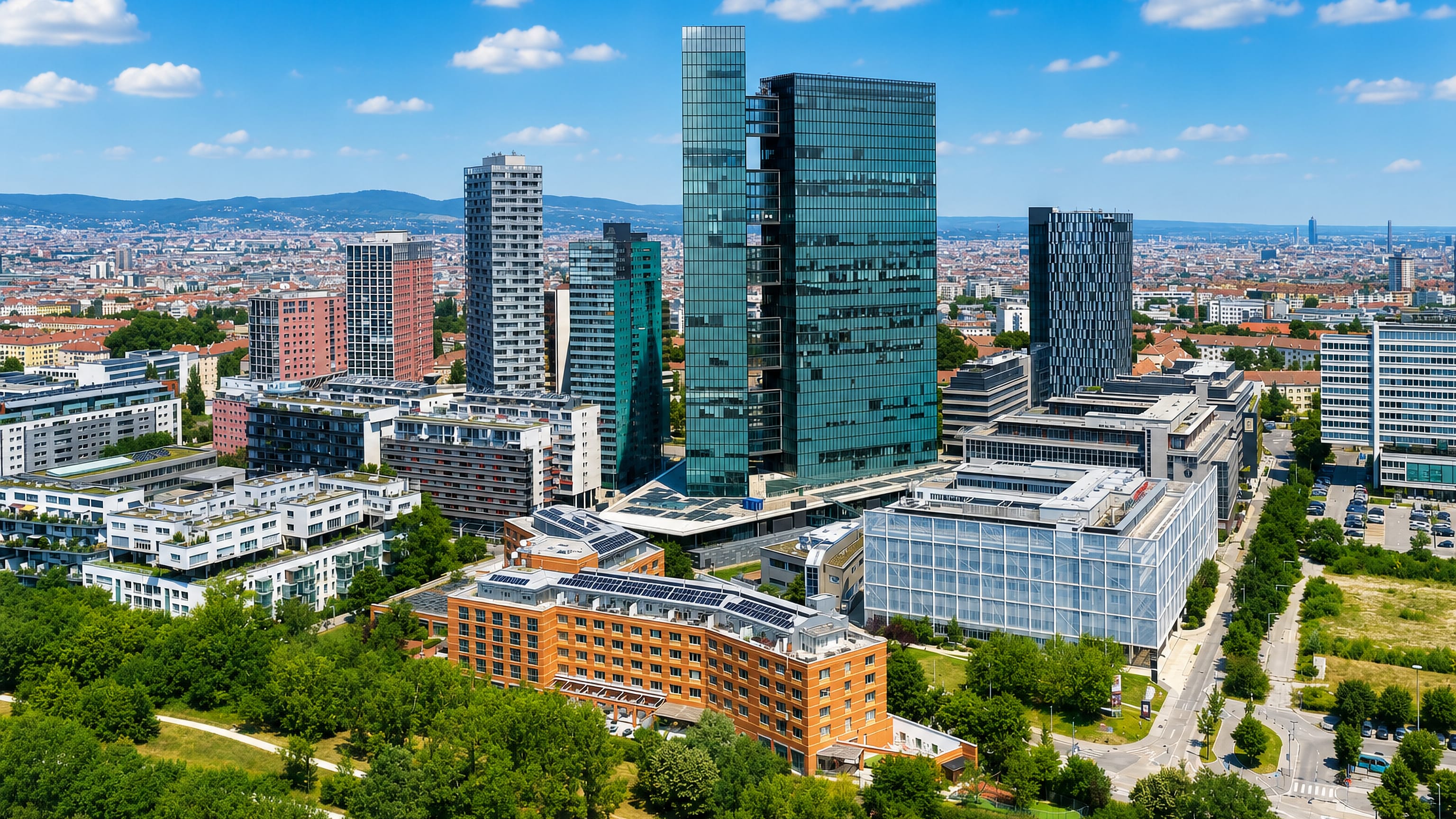 Aerial view of the Wienerberg high-rises in Favoriten, Vienna, with the city and hills beyond.