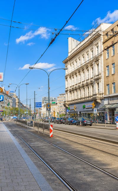 Street-level view of a Vienna avenue at Europaplatz in Fuenfhaus with tram tracks, shopfronts and cafe signage
