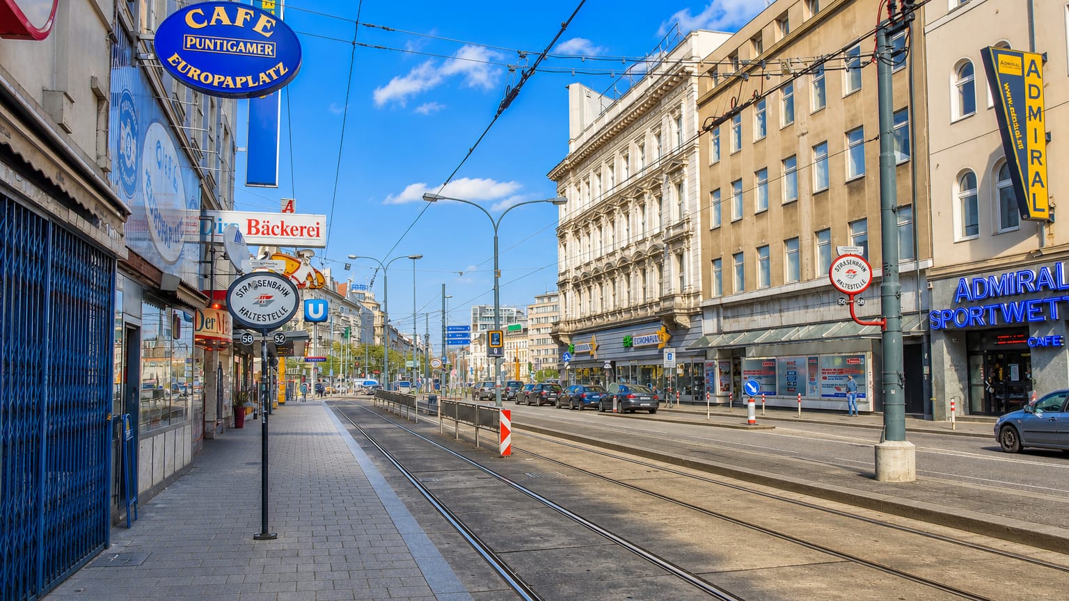 Street-level view of a Vienna avenue at Europaplatz in Fuenfhaus with tram tracks, shopfronts and cafe signage