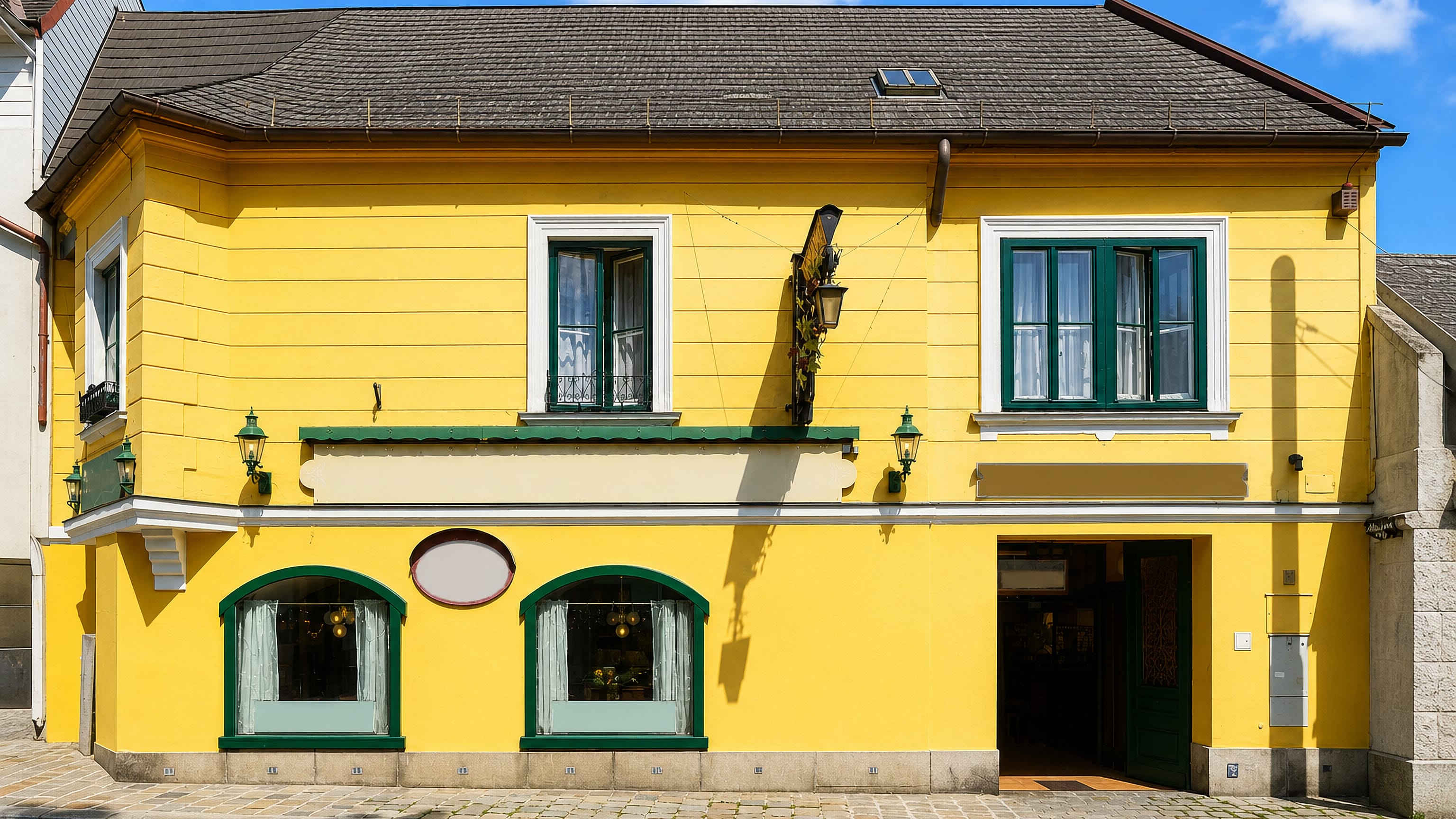 Yellow Heuriger tavern with green shutters on a cobbled lane in Grinzing, Vienna.