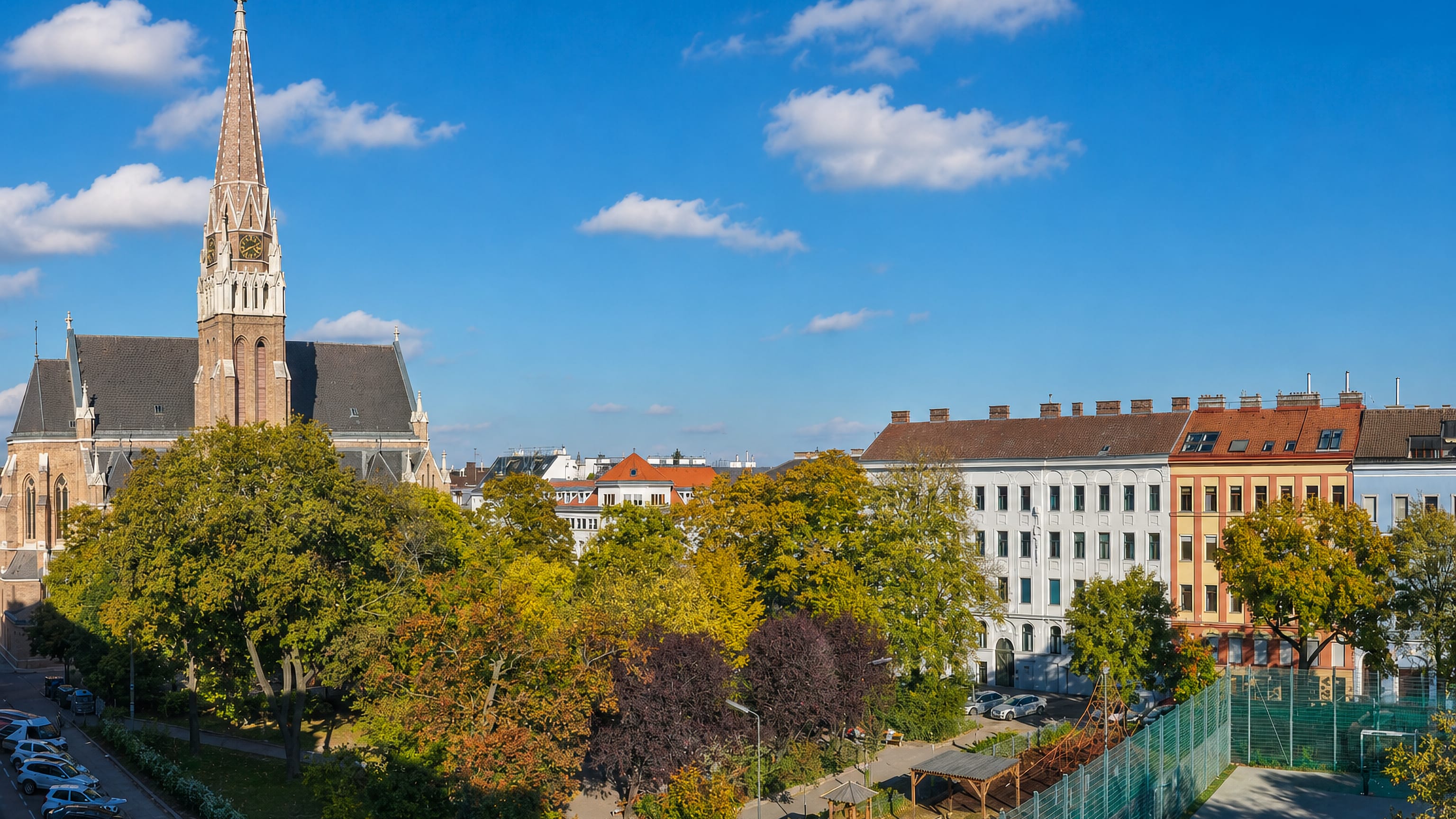 Neo-Gothic brick church spire above tree-lined Gruenderzeit apartment blocks in Hernals, Vienna's 17th district.