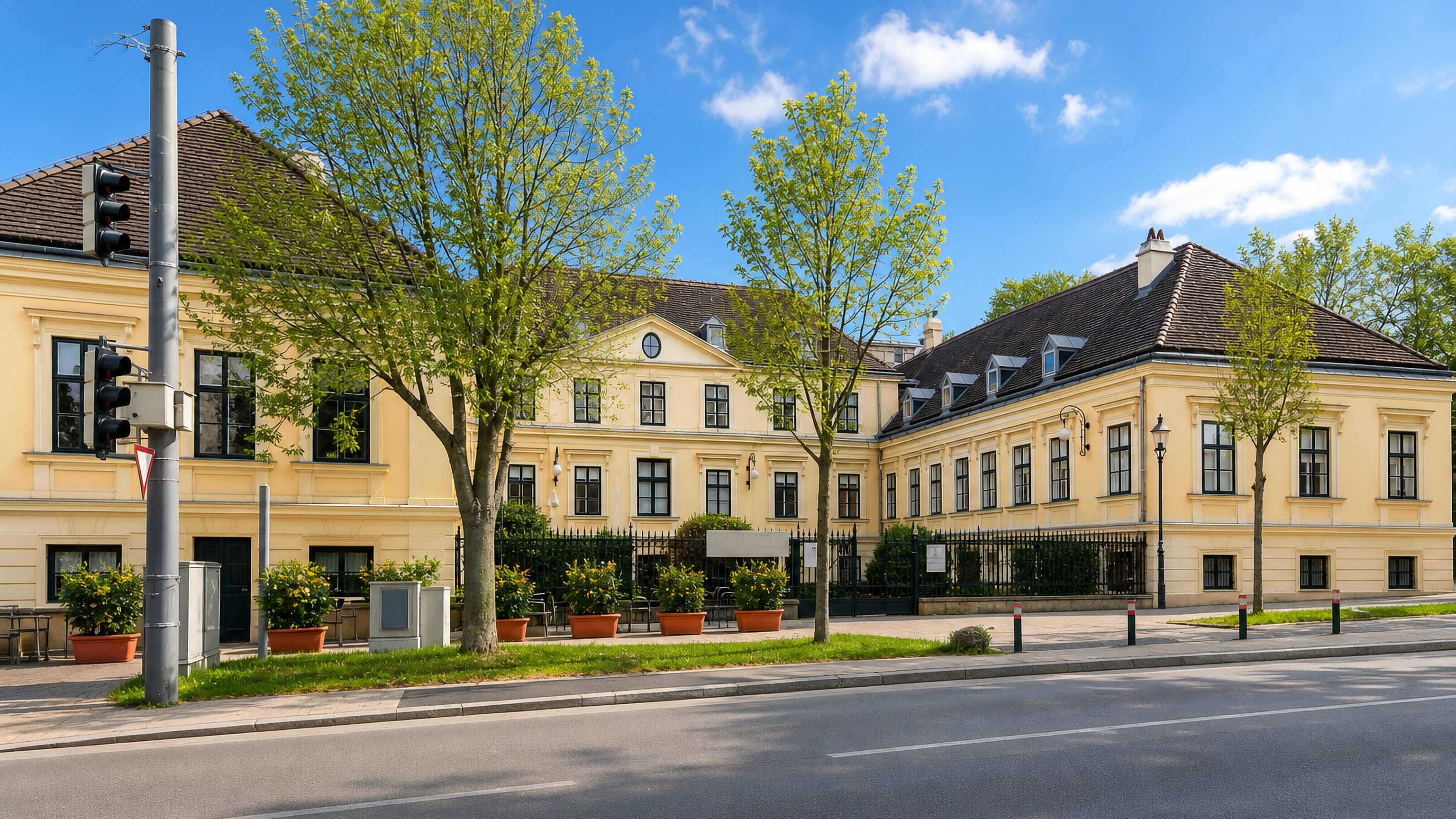 Schloss Hetzendorf's long yellow Baroque facade behind iron railings on a quiet street in Hetzendorf, Vienna.