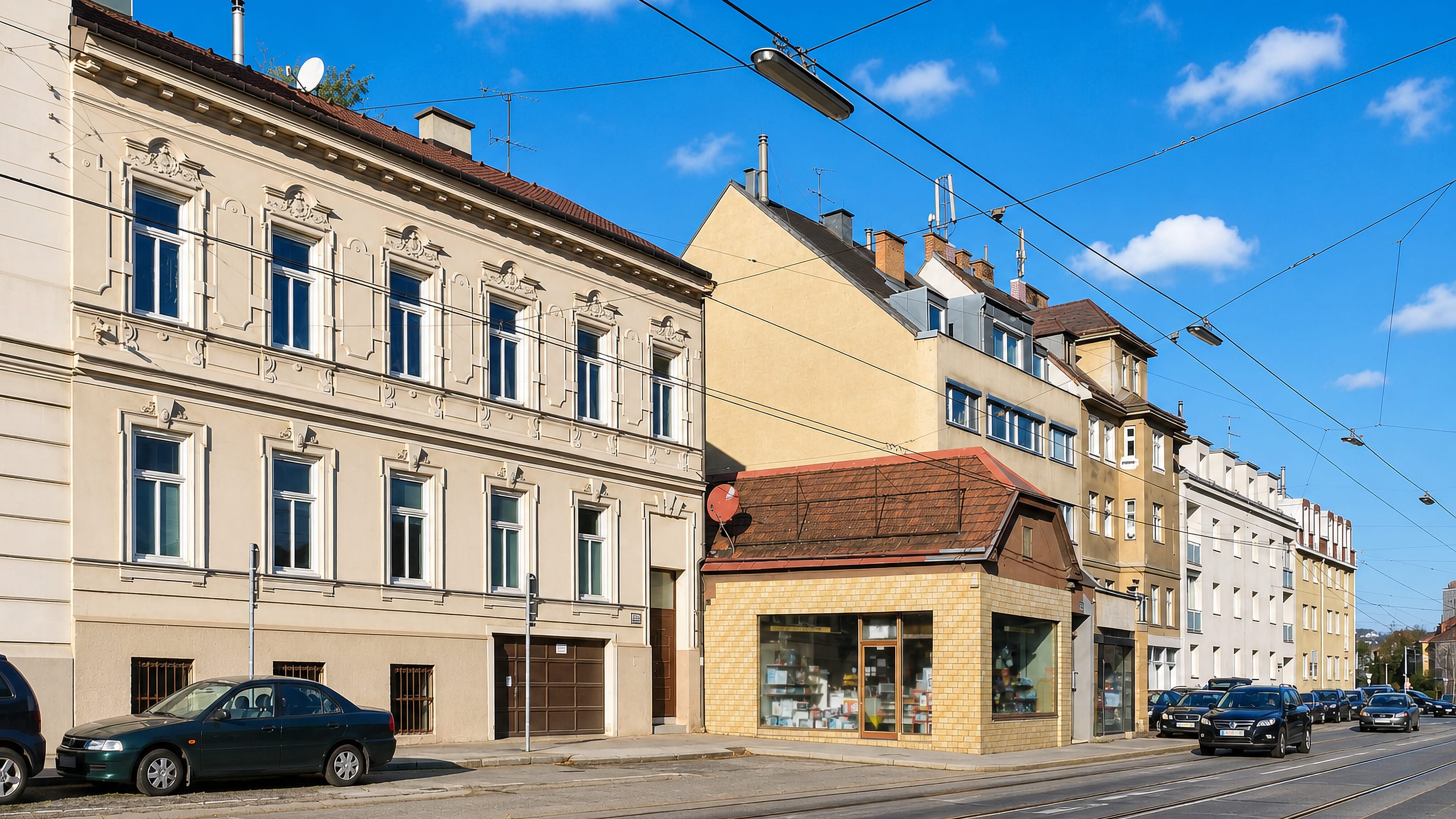 Tram tracks running past pastel Gründerzeit apartment houses and a corner shop in Lainz, Vienna.