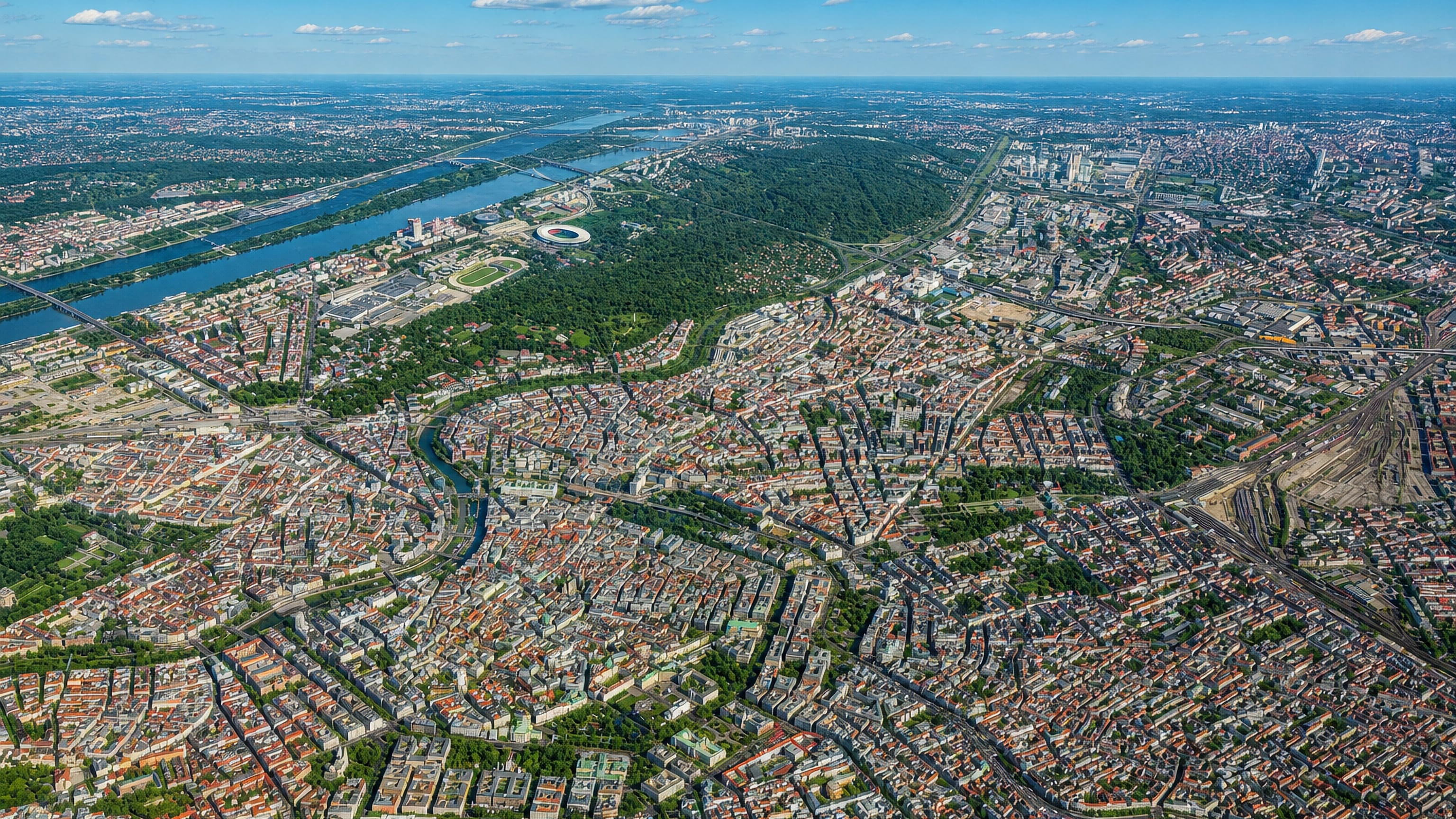 High aerial over Vienna's inner districts around Margareten, with the Danube and the Prater beyond