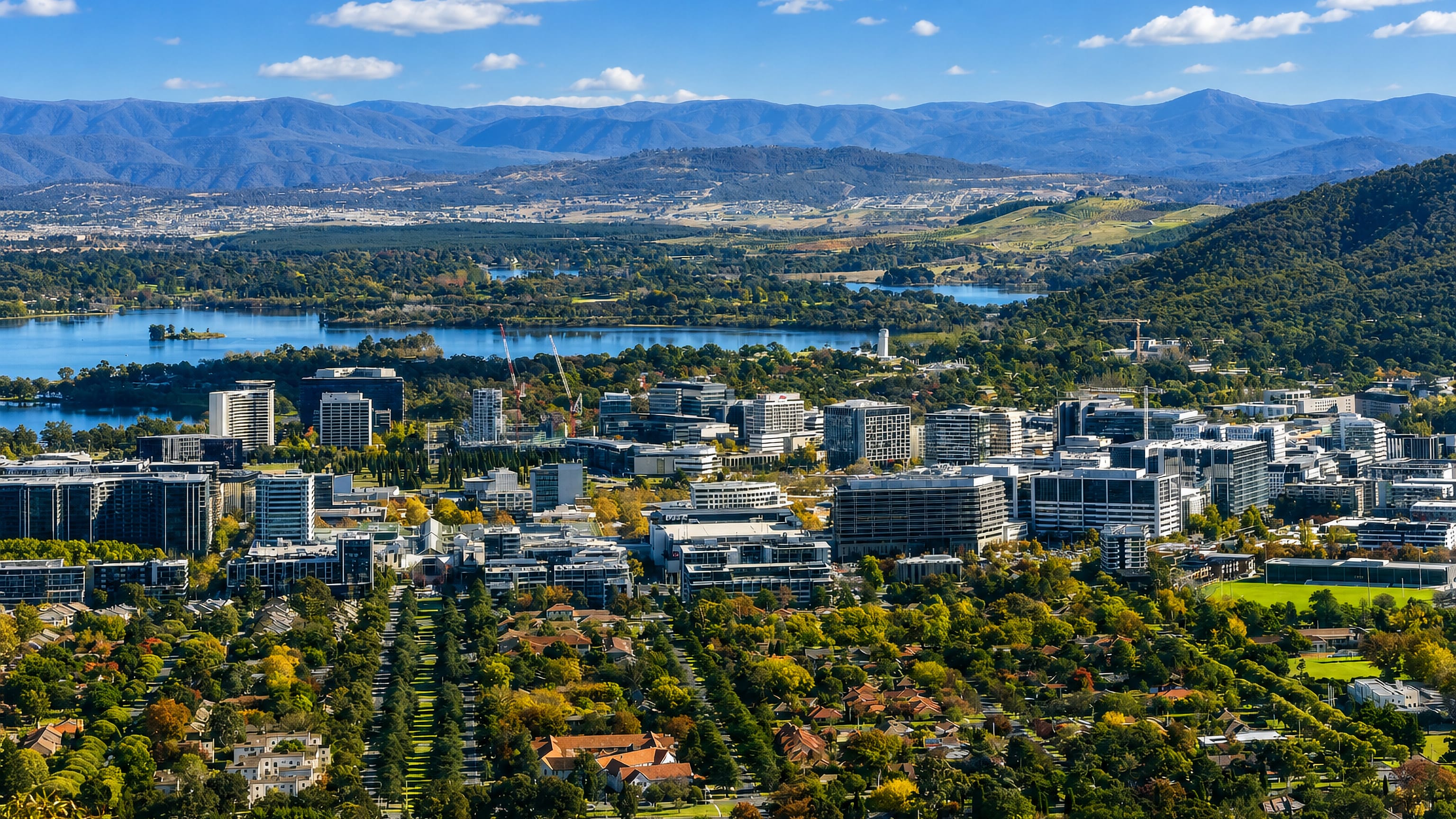 Canberra City from above, with Civic office towers, Lake Burley Griffin and the Brindabella ranges beyond.
