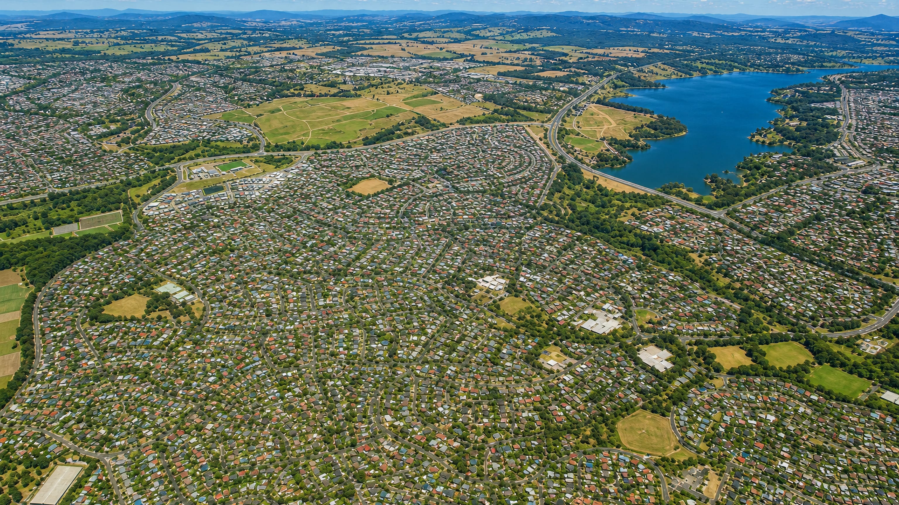 Aerial view of Evatt in Canberra, with tree-lined suburban streets stretching to Lake Ginninderra.