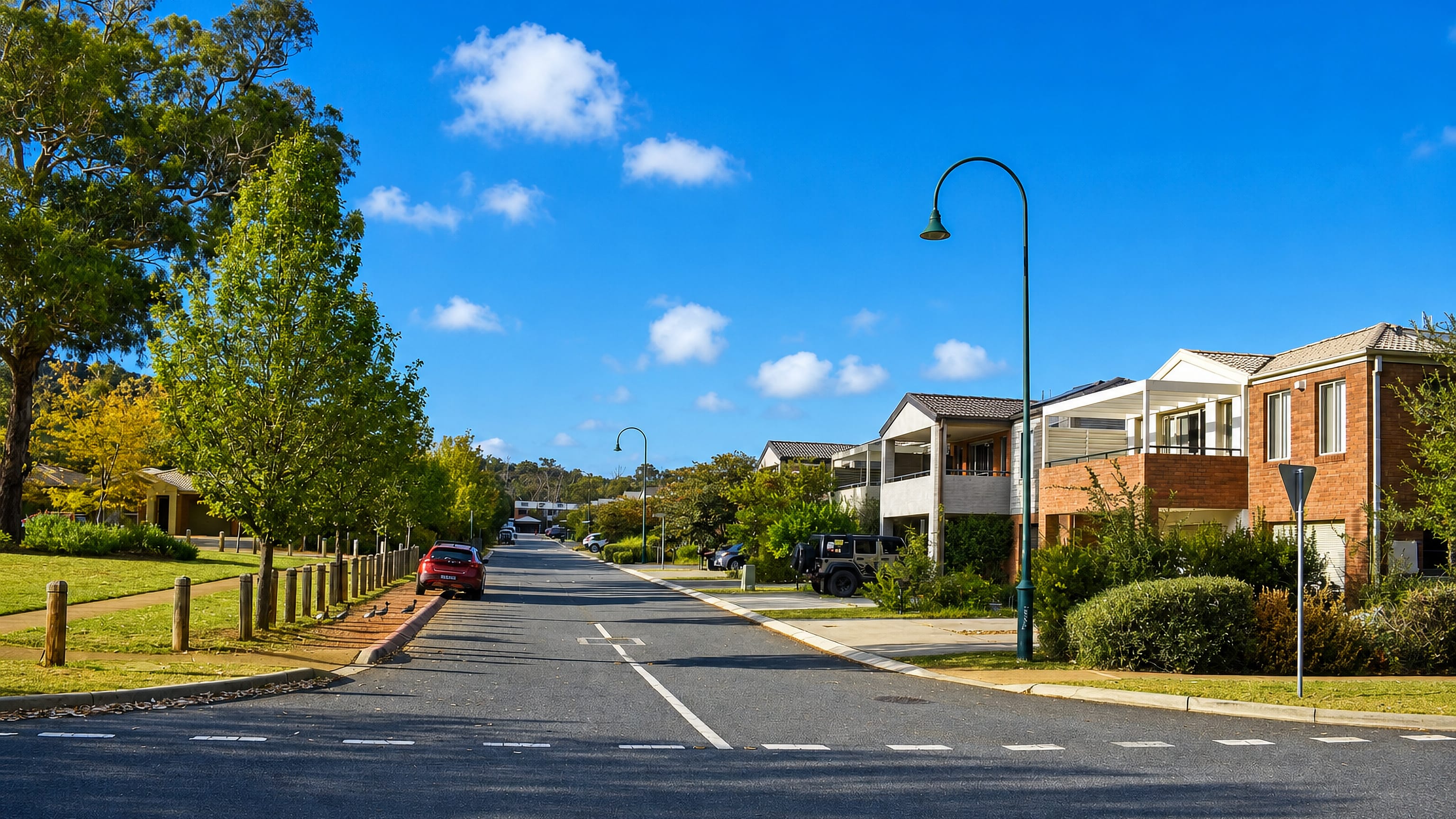 A quiet tree-lined residential street in Watson, Canberra, with brick townhouses.