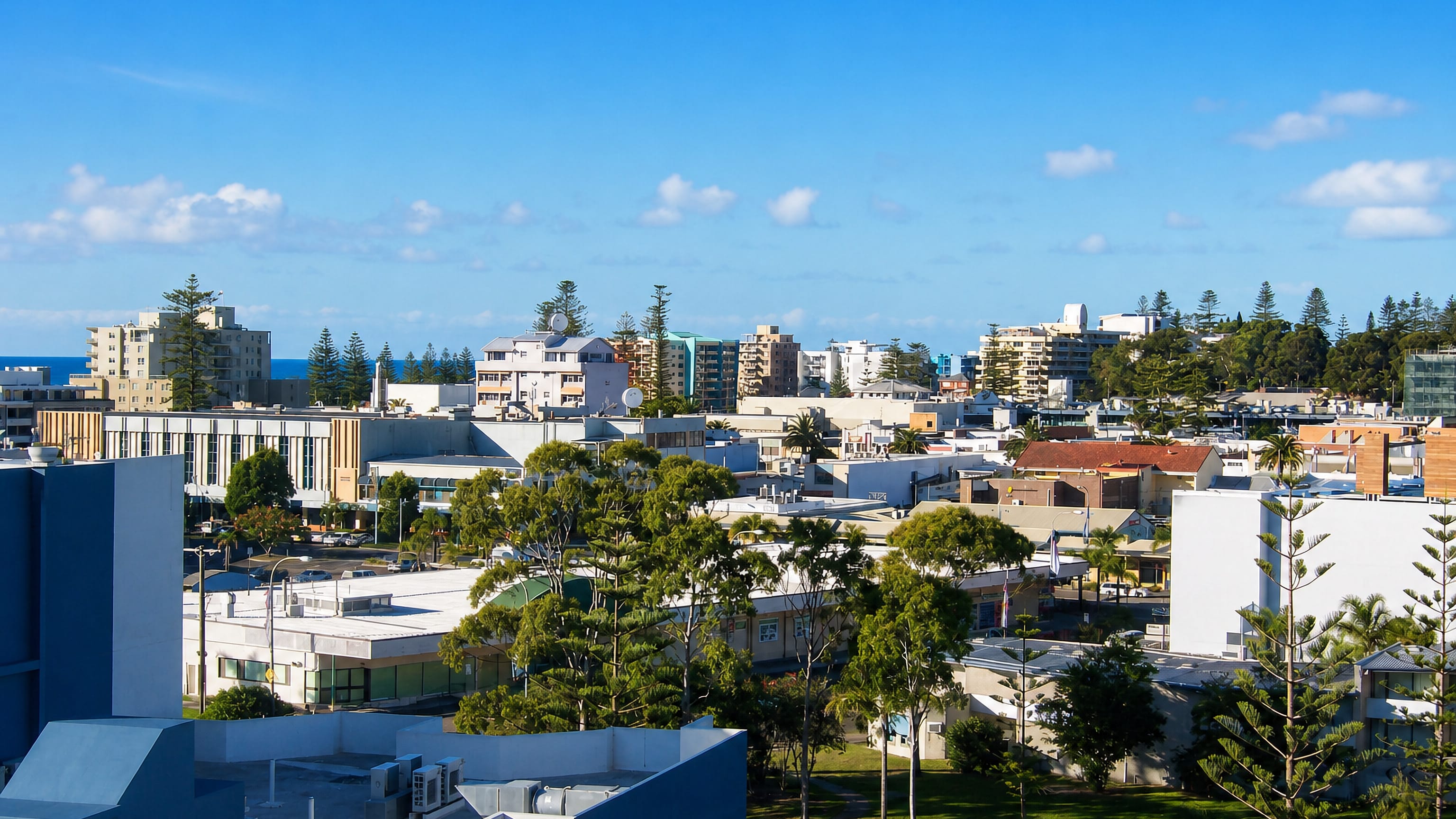Low-rise centre of Port Macquarie, Australia, with Norfolk Island pines and the ocean on the horizon.