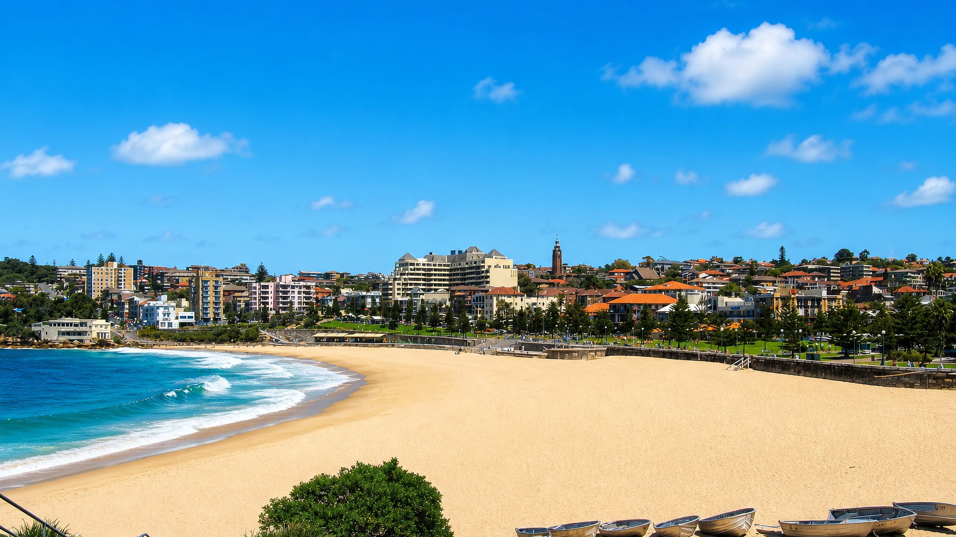 Coogee Beach in Sydney curving between headlands, with surf boats on the sand and terraced houses above the bay.