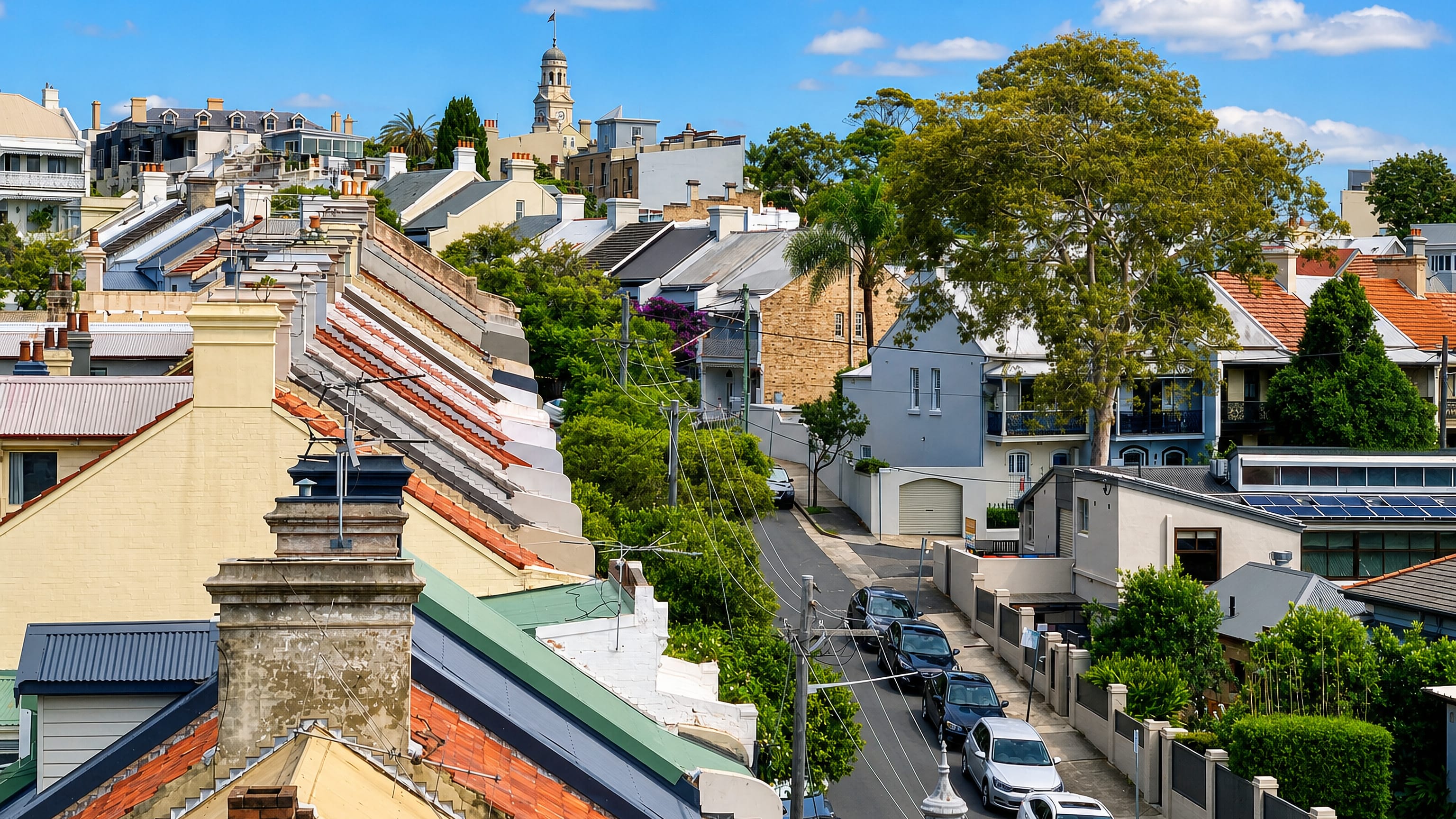 Victorian terrace rooftops and iron-lace verandahs stepping down a leafy street in Paddington, Sydney.