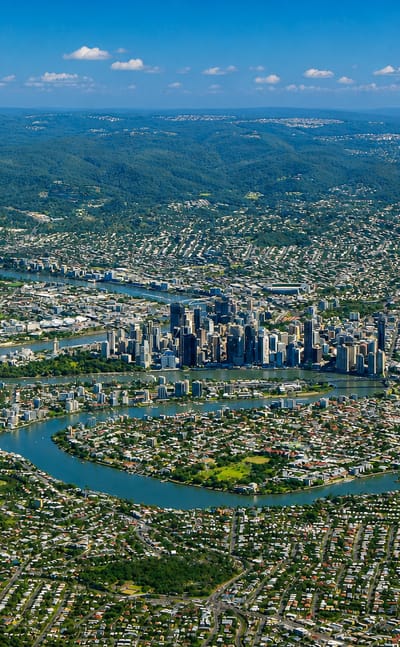 Aerial view over East Brisbane suburbs and the winding Brisbane River toward the city centre.