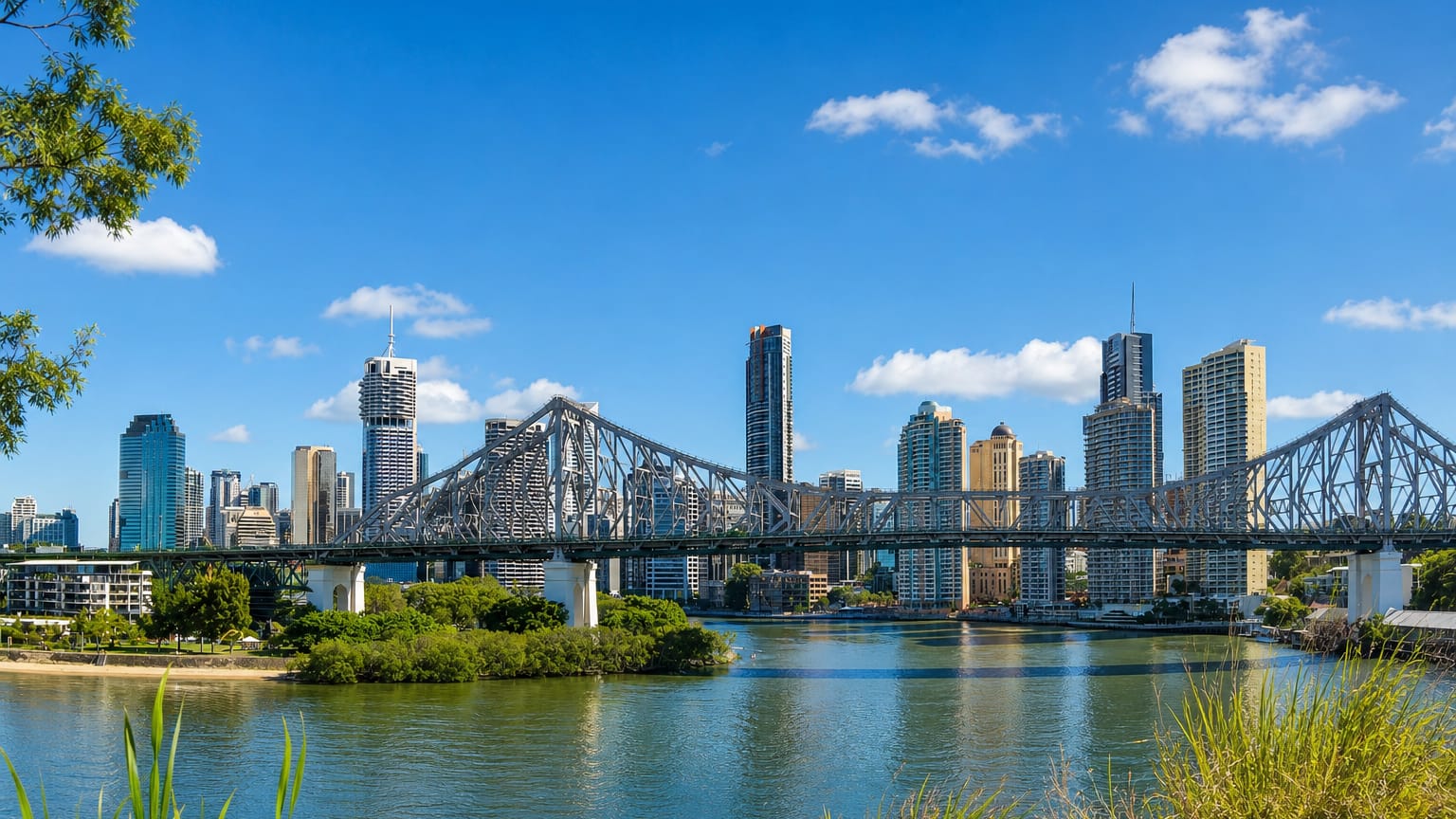 Brisbane's Story Bridge and CBD skyline rising above the Brisbane River, framed by riverside greenery.