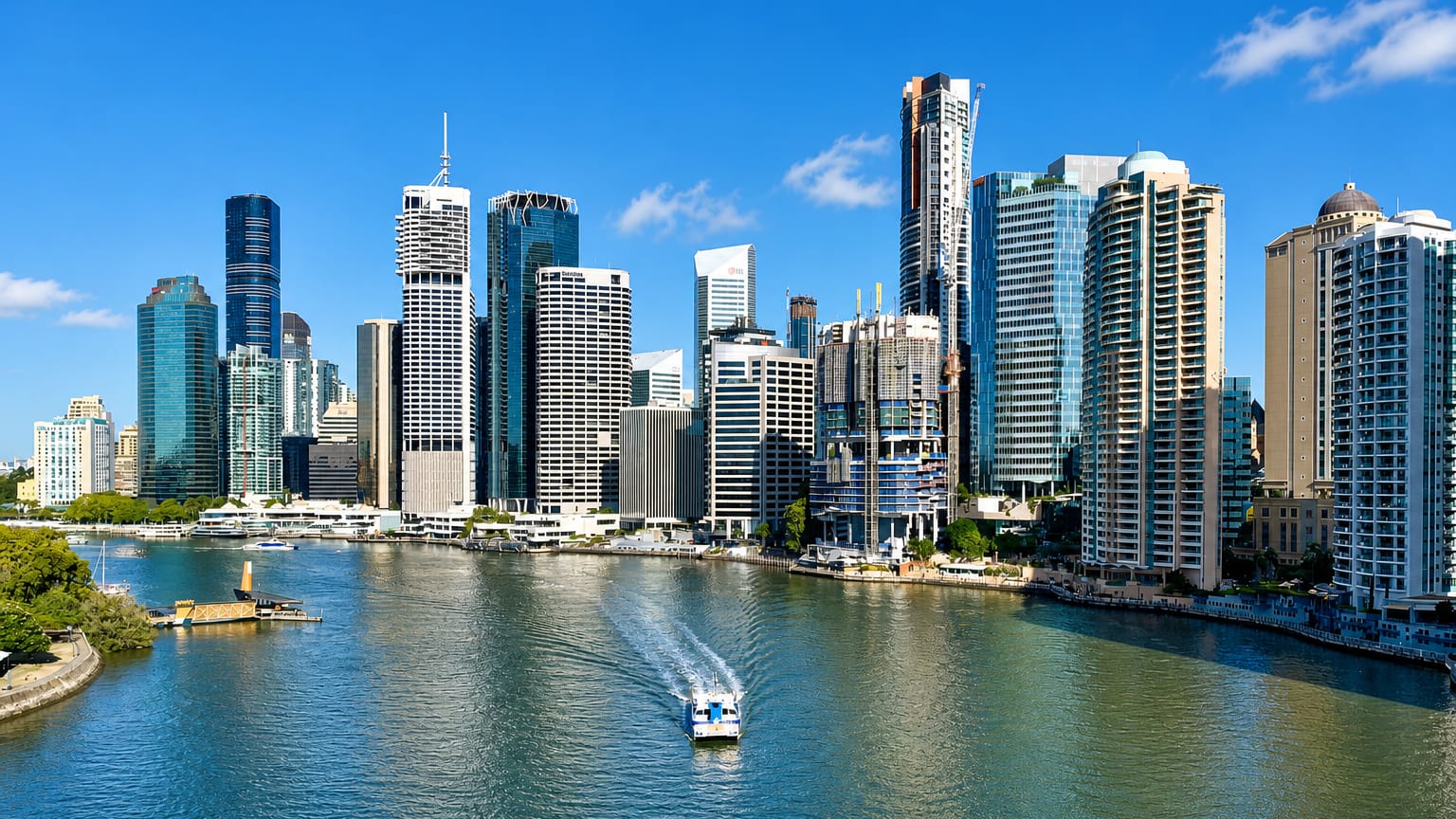 Brisbane CBD skyline of glass towers across the Brisbane River, seen from Kangaroo Point with a CityCat ferry passing
