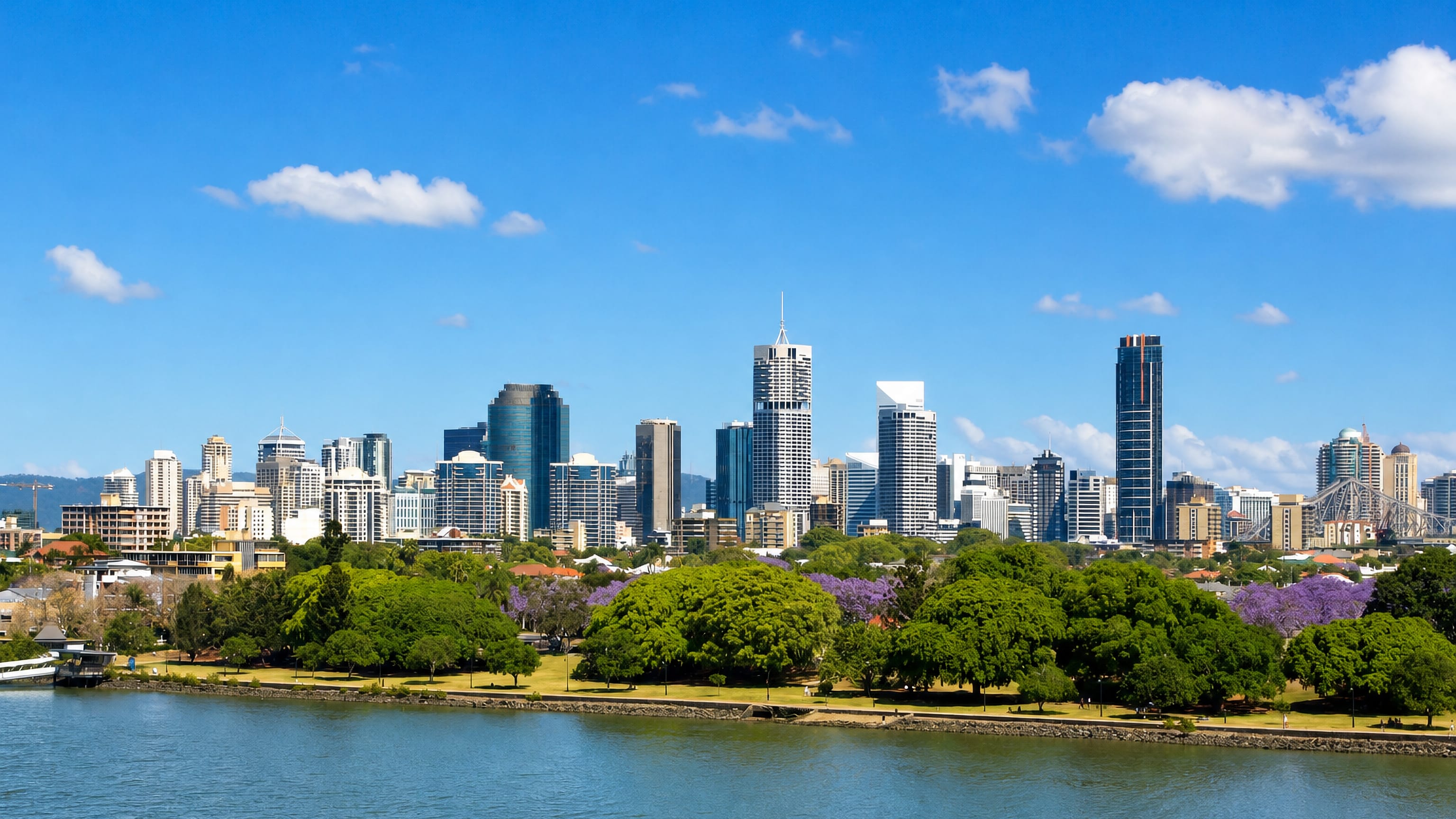 Brisbane CBD skyline and Story Bridge seen across the Brisbane River from riverside parkland at Norman Park.