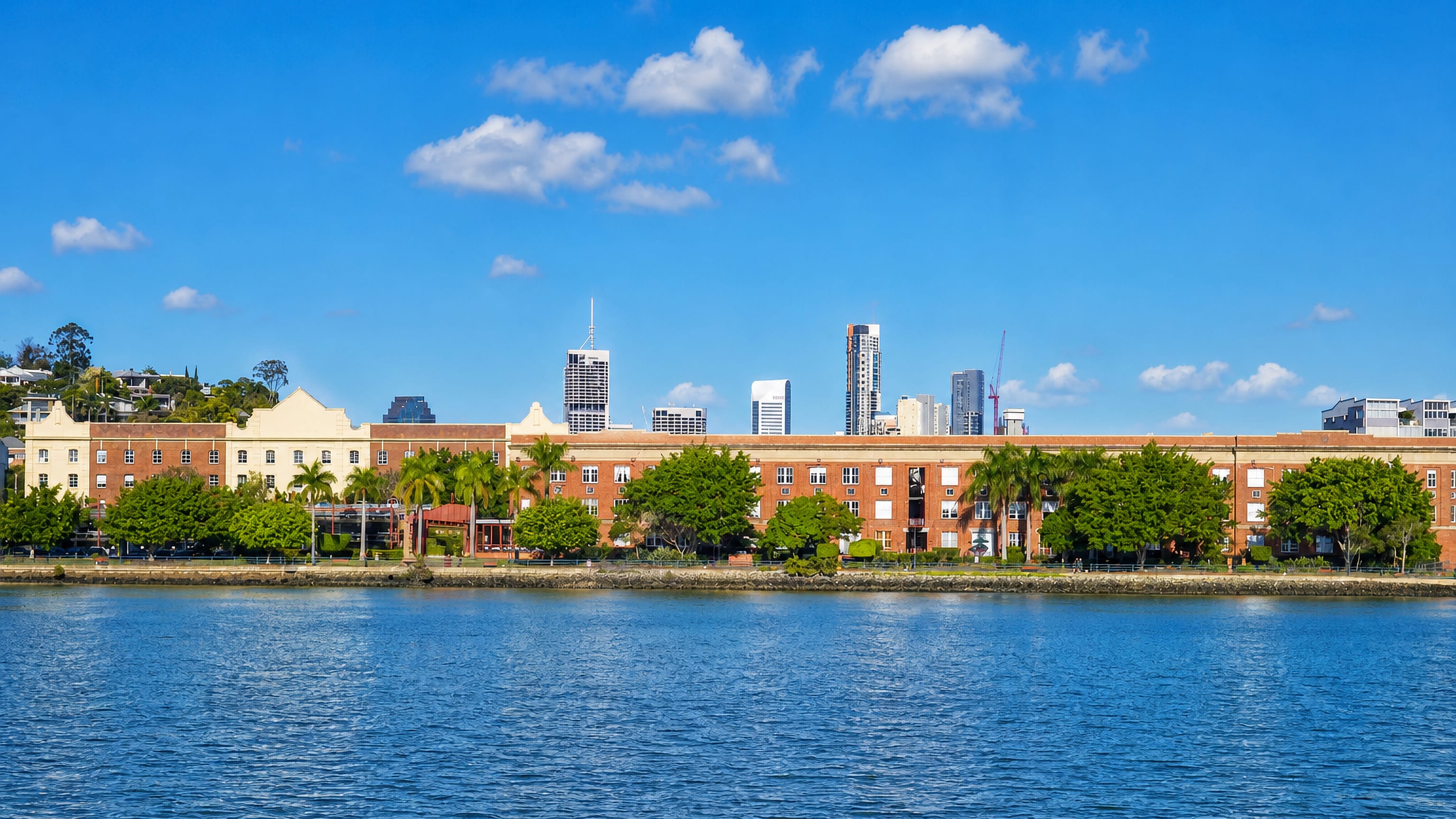 Heritage brick woolstores along the Brisbane River at Teneriffe, with the city skyline behind