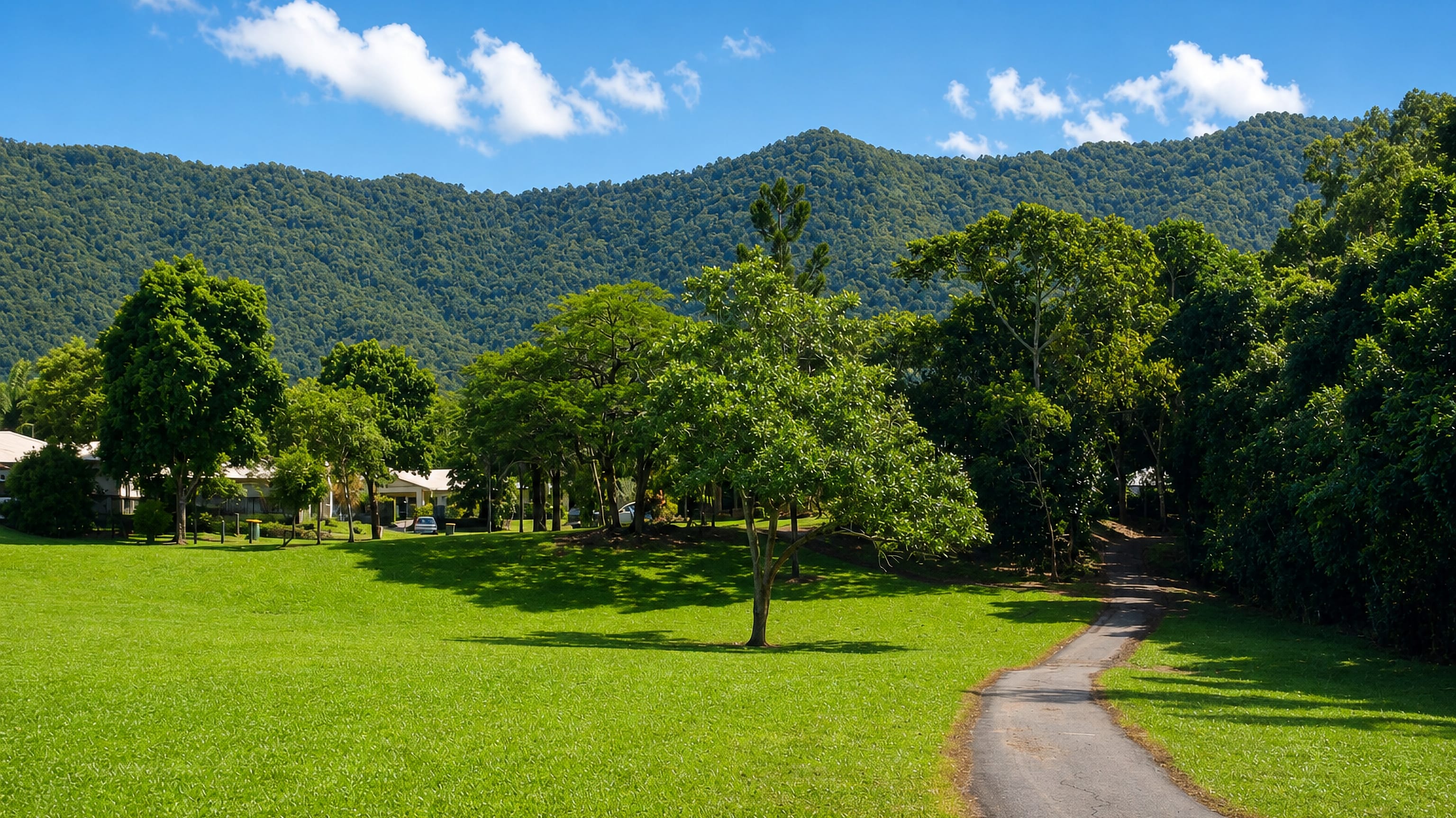 Parkland lawn and footpath below rainforest-clad ranges in Bentley Park, a southern suburb of Cairns.