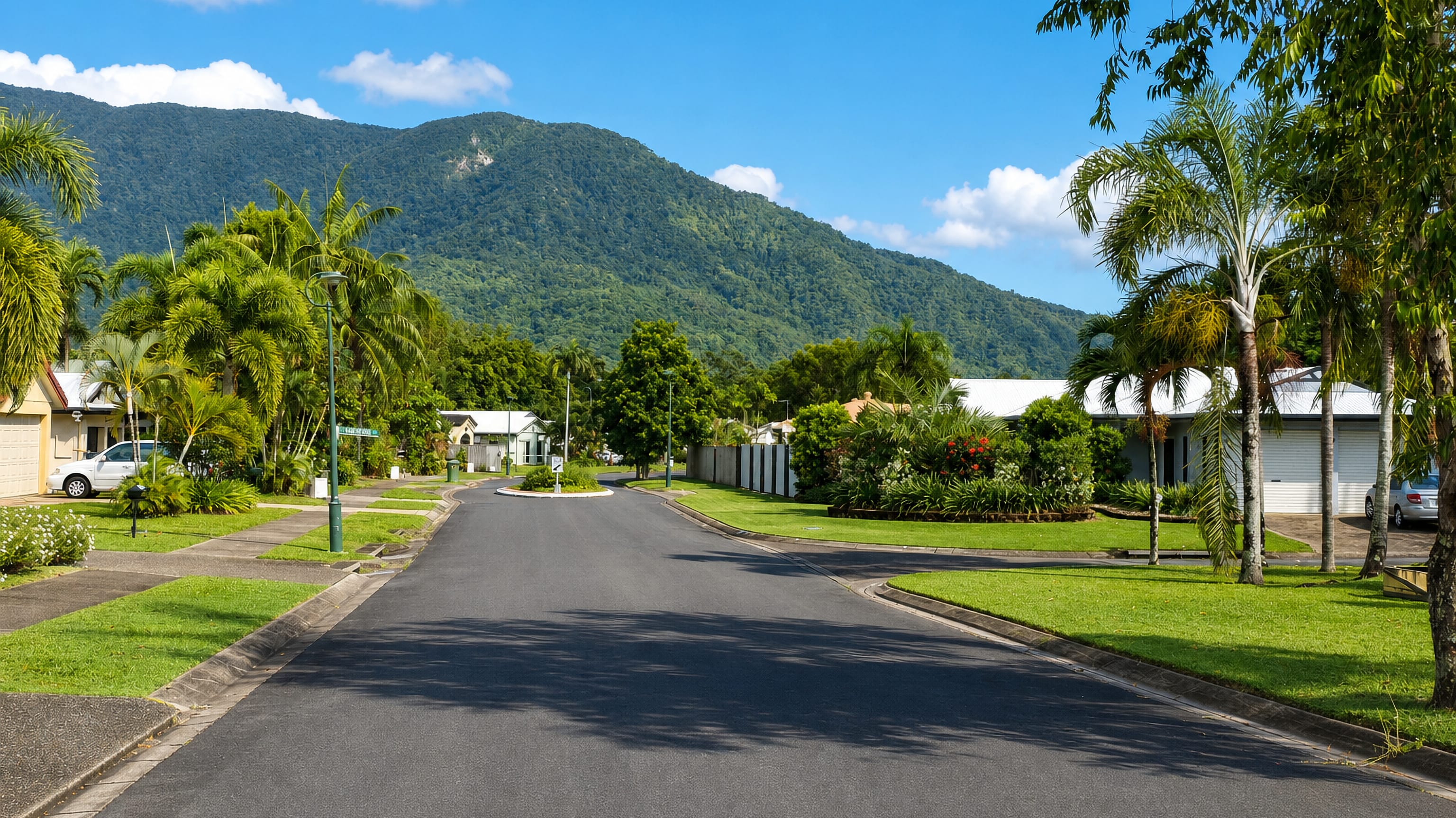 Palm-lined residential street in Brinsmead, Cairns, below the rainforest-covered Whitfield range.
