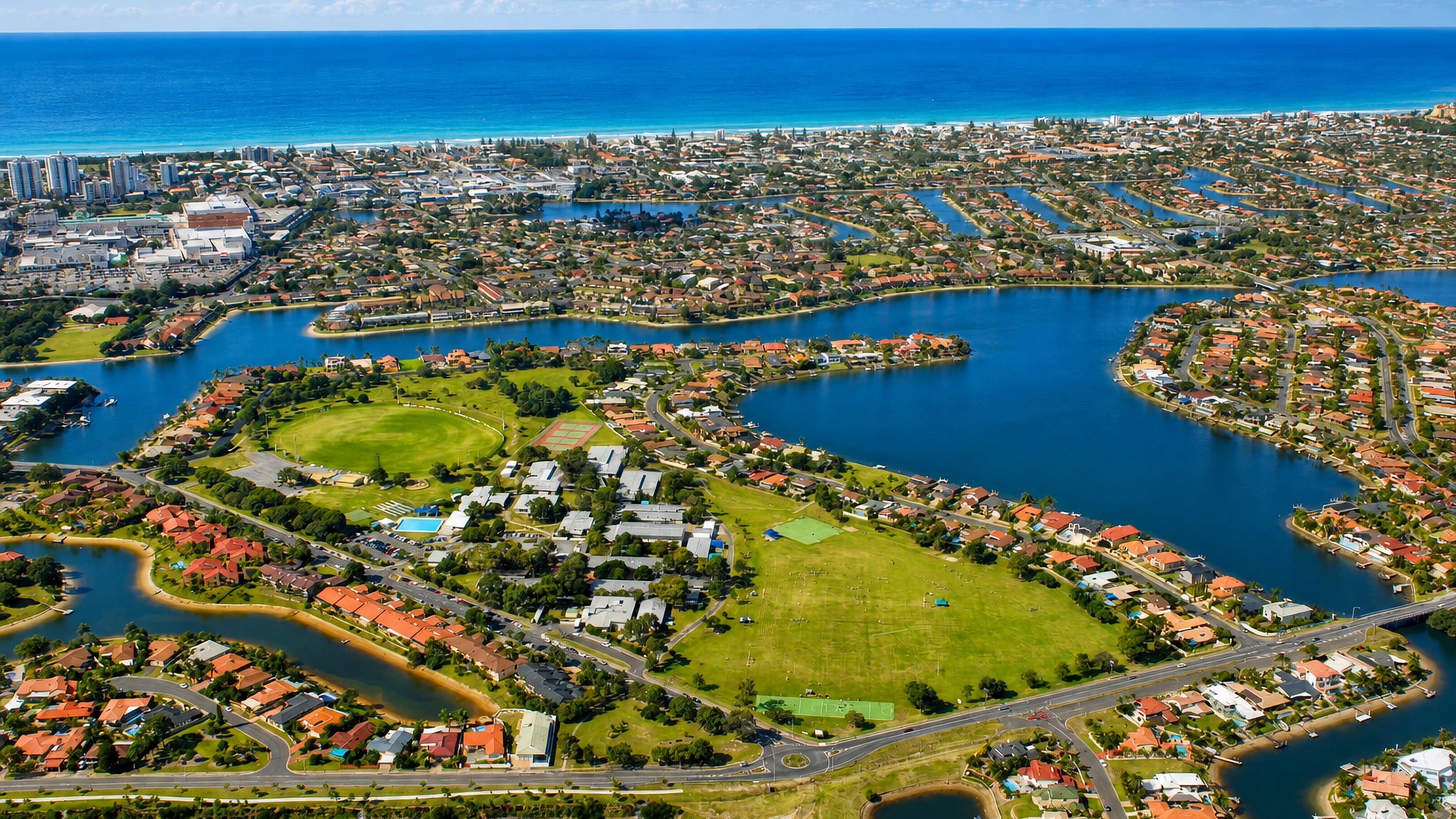 Aerial view of Mermaid Waters' canals, parks and waterfront homes behind Mermaid Beach on the Gold Coast