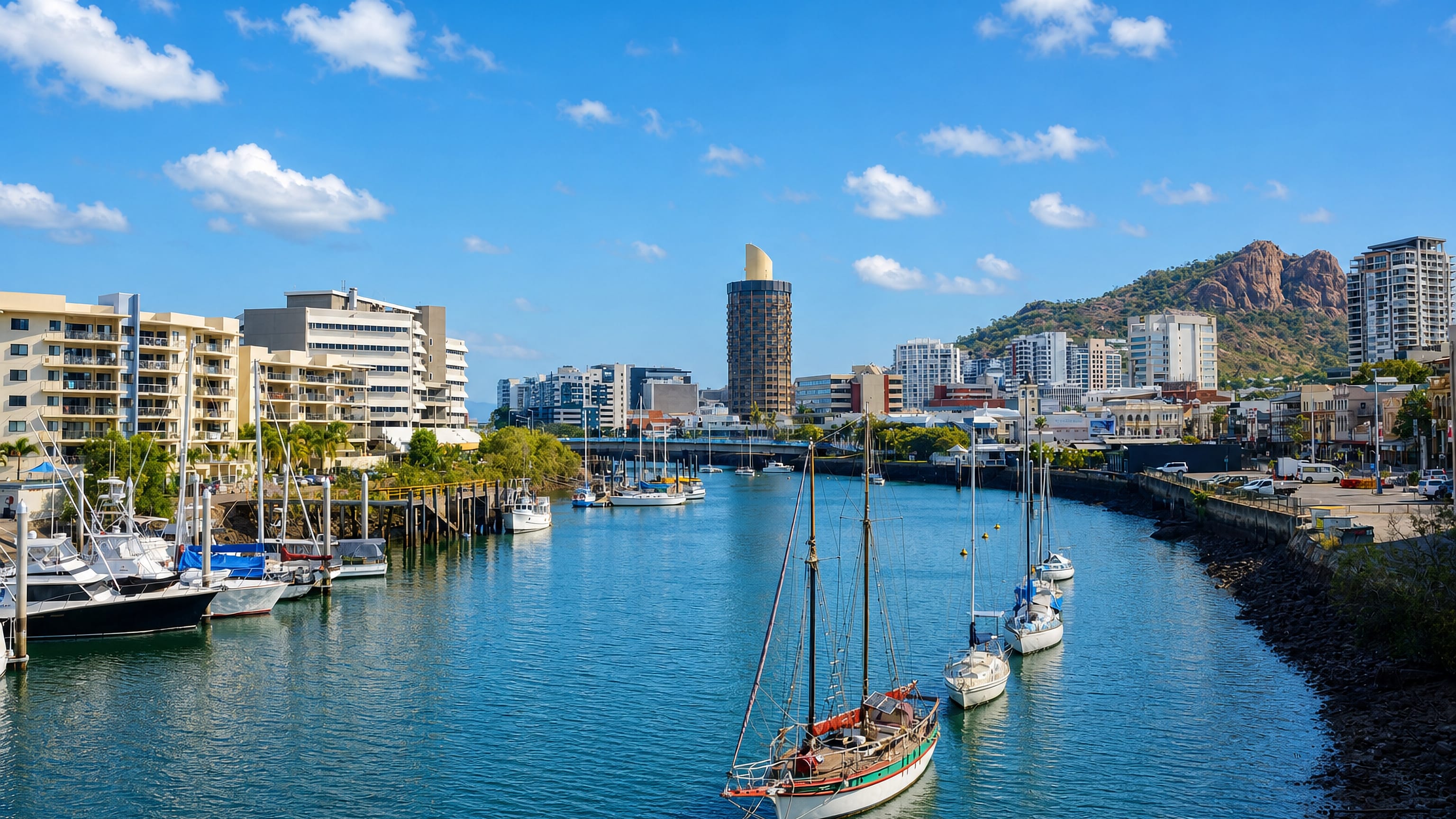 Yachts moored on Ross Creek below Townsville's waterfront towers and the red granite dome of Castle Hill.