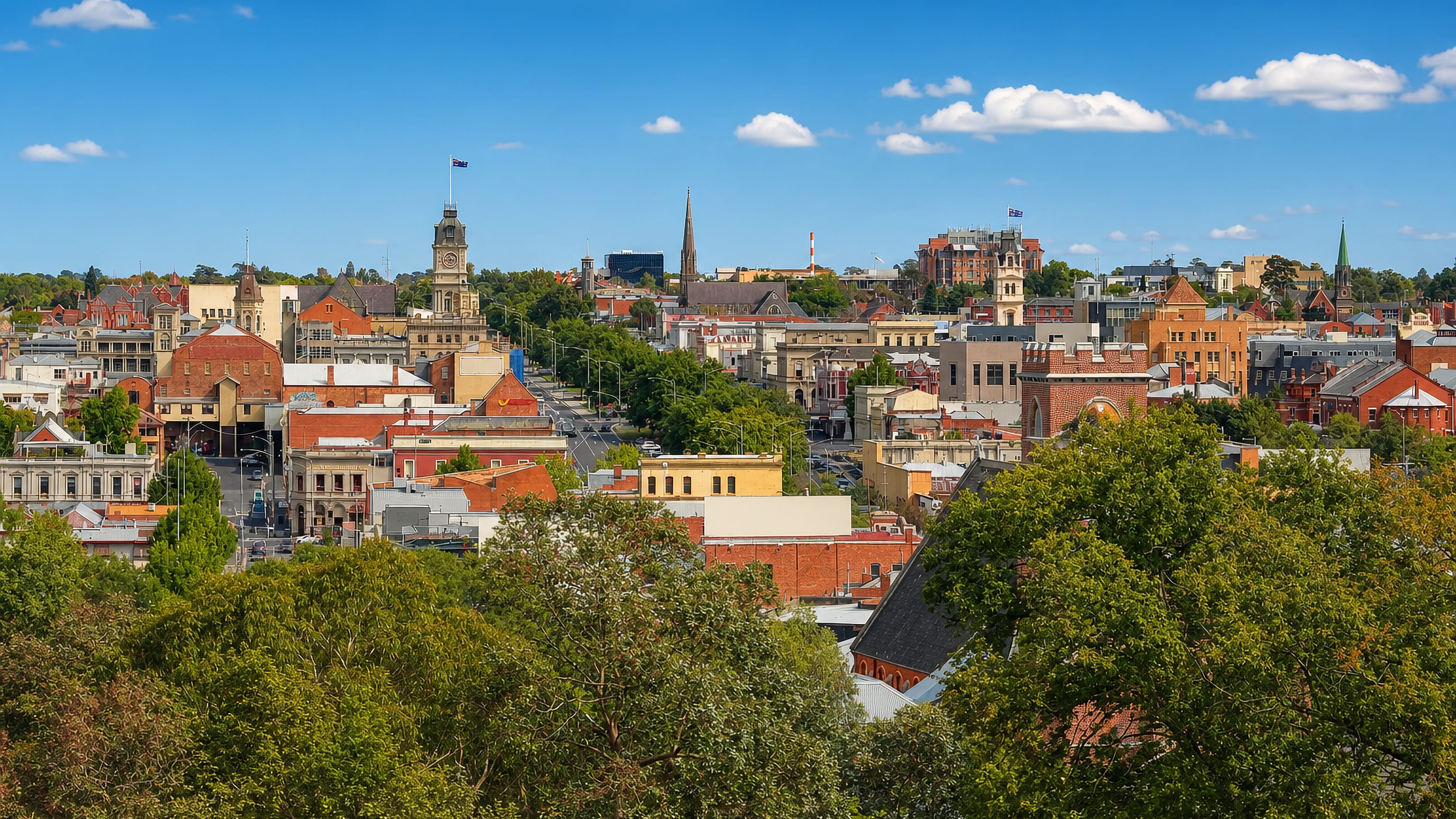 Ballarat's Victorian-era rooftops and the Town Hall clock tower above leafy treetops in central Victoria, Australia