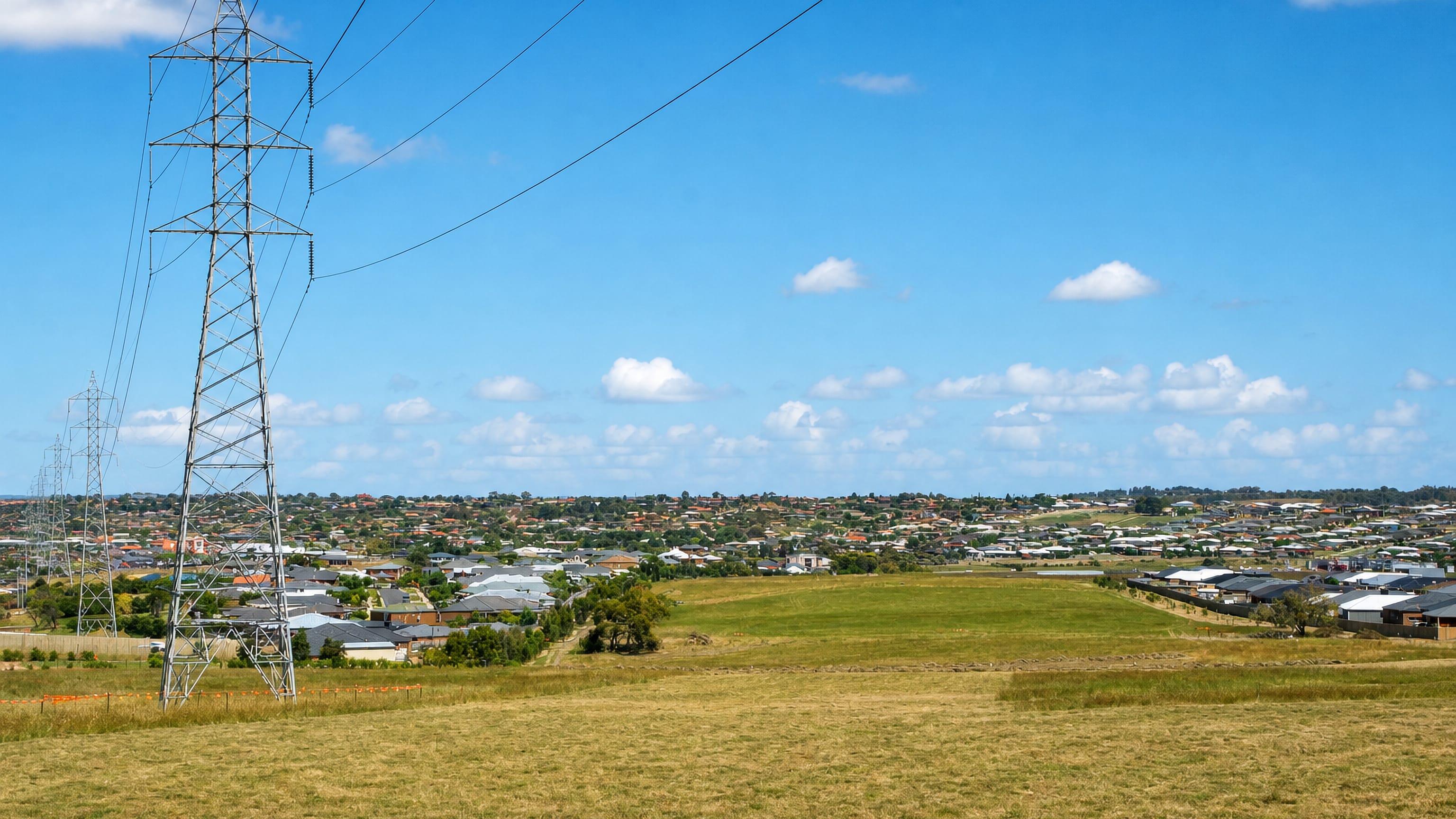 Open paddock and a transmission pylon at the edge of Grovedale's housing estates in Geelong, Australia