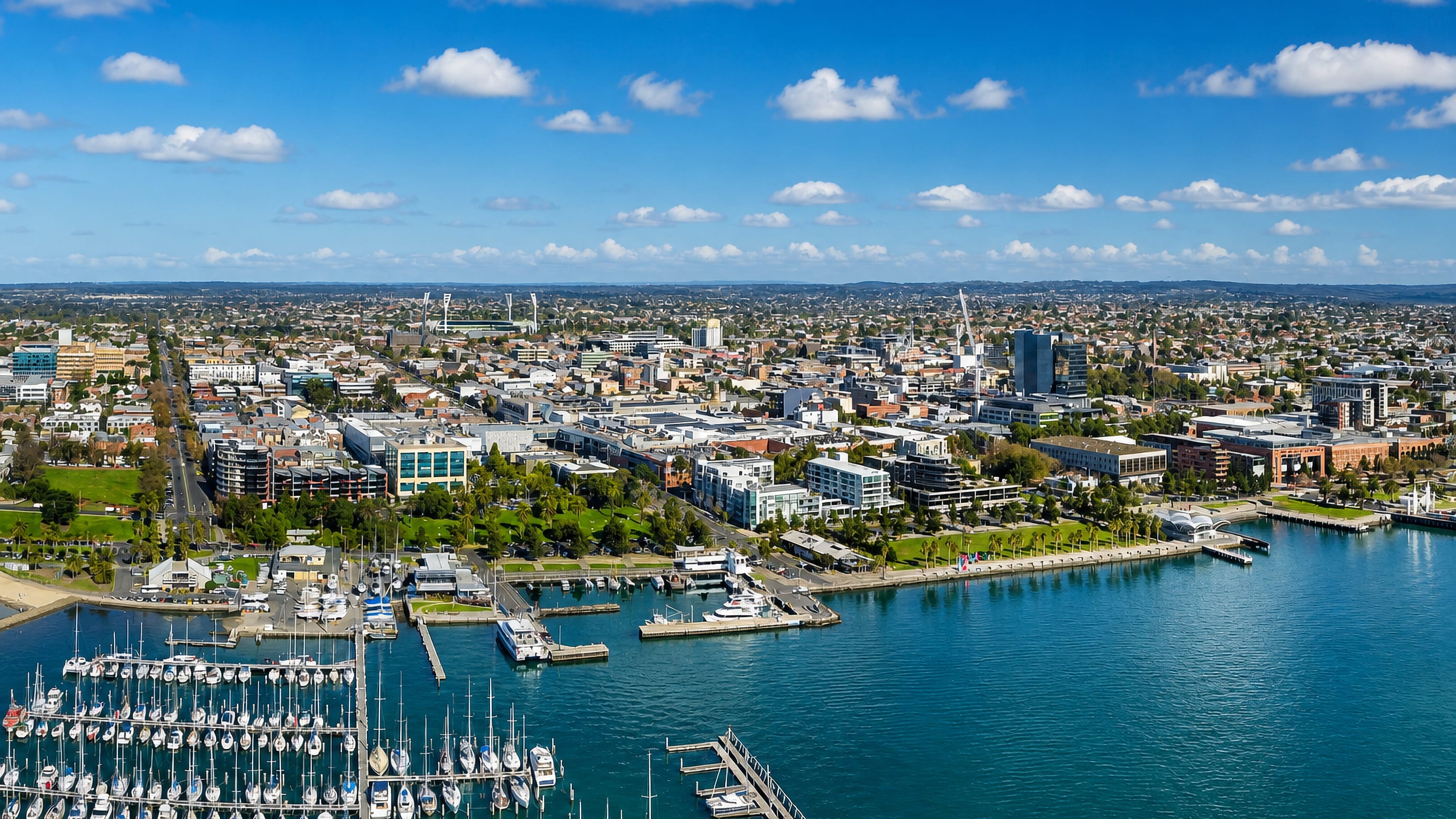 Geelong's waterfront and city centre above Corio Bay, with the yacht club marina and stadium light towers.